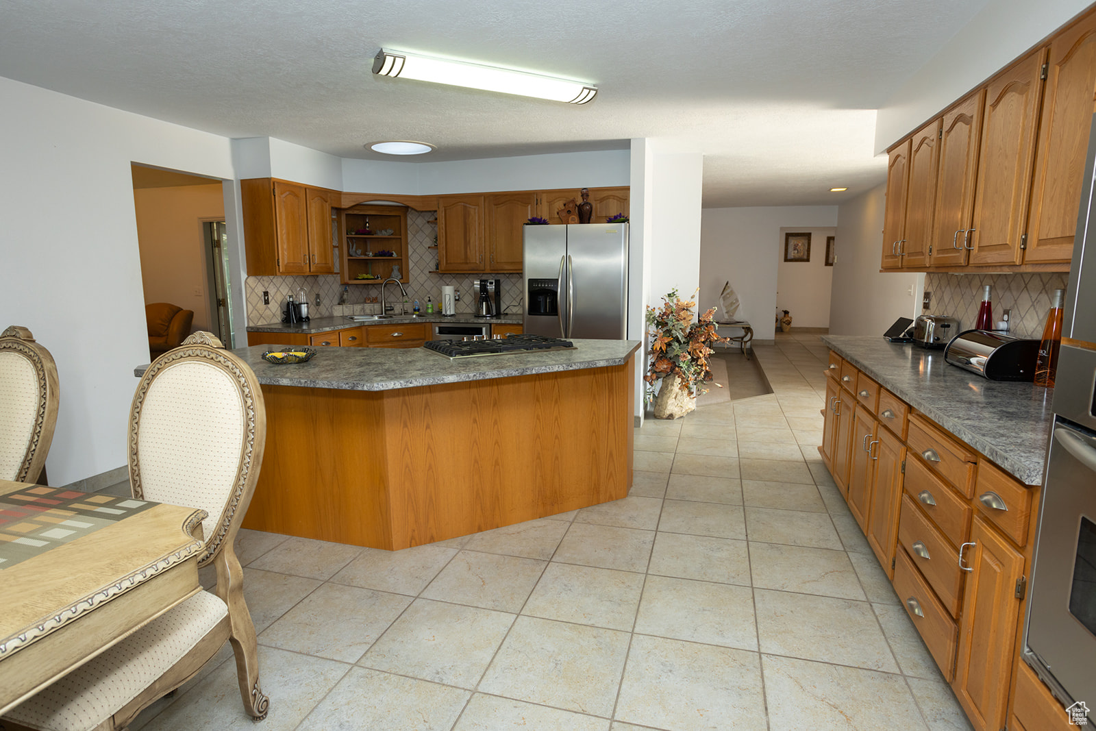 Kitchen featuring stainless steel appliances, sink, light tile patterned floors, and backsplash