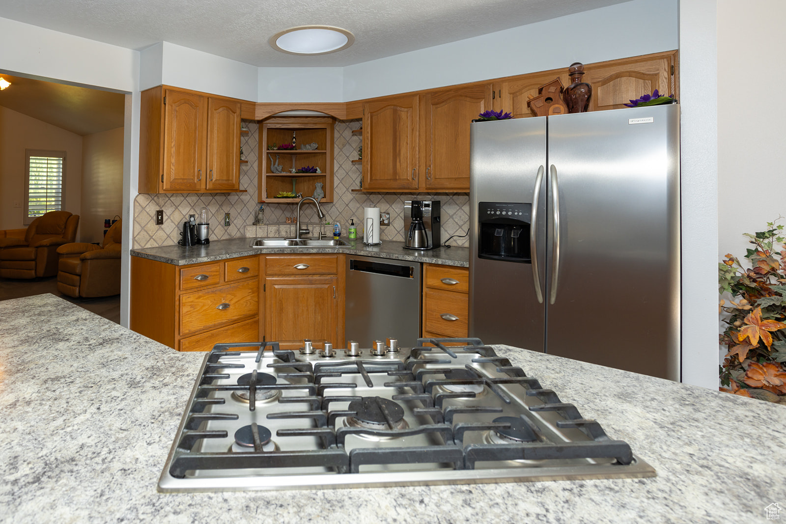 Kitchen with a textured ceiling, appliances with stainless steel finishes, tasteful backsplash, sink, and lofted ceiling