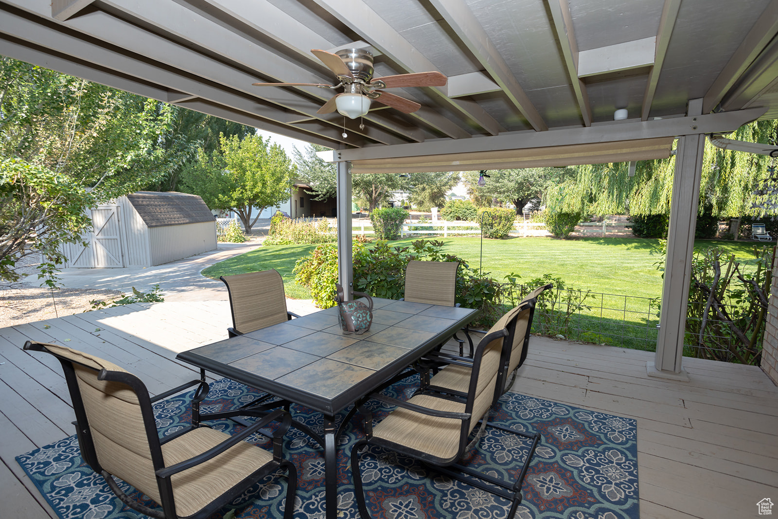 Deck with a lawn, ceiling fan, and a shed