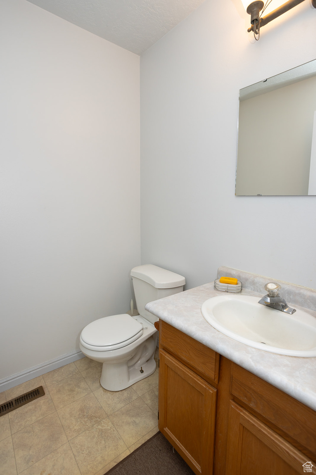 Bathroom featuring vanity, toilet, and tile patterned floors