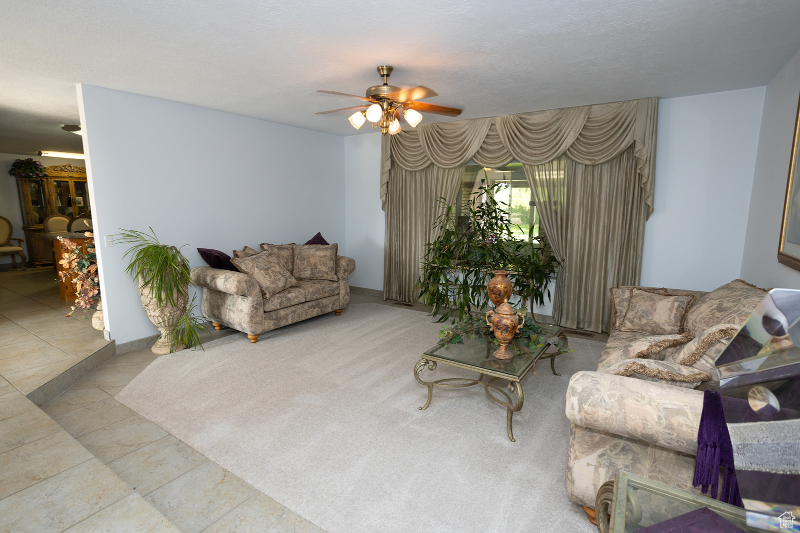 Tiled living room with ceiling fan and a textured ceiling