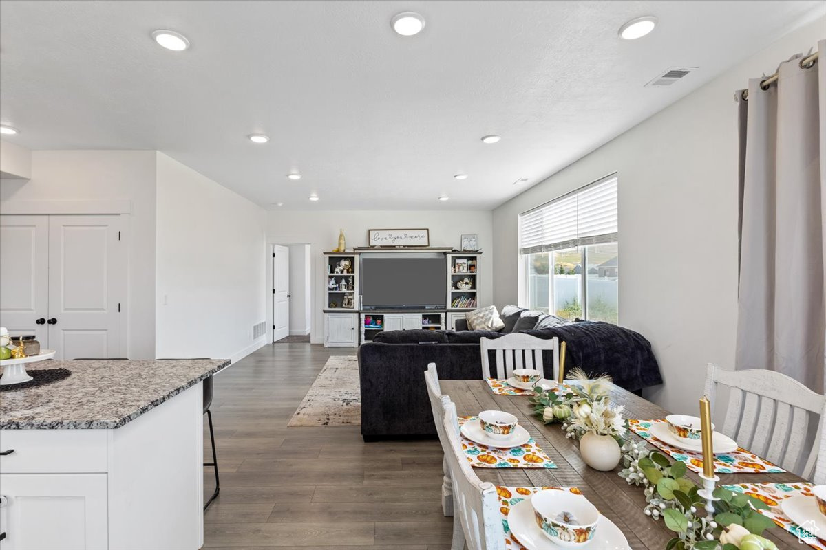 Kitchen featuring dark wood-type flooring, white cabinets, light stone countertops, and a breakfast bar