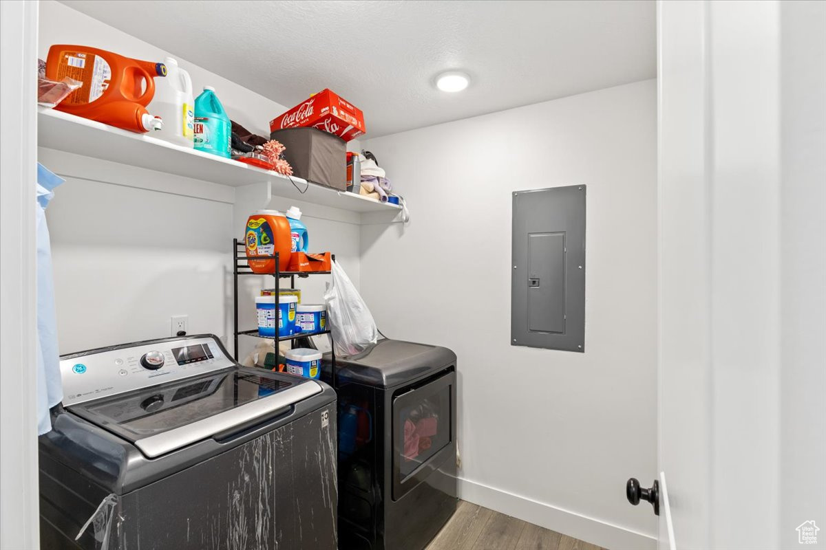 Laundry room with hardwood / wood-style flooring, independent washer and dryer, and electric panel