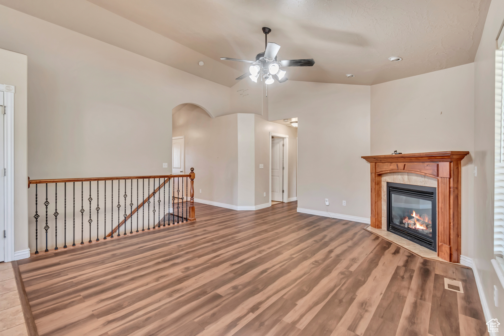 Unfurnished living room featuring lofted ceiling, ceiling fan, and wood-type flooring