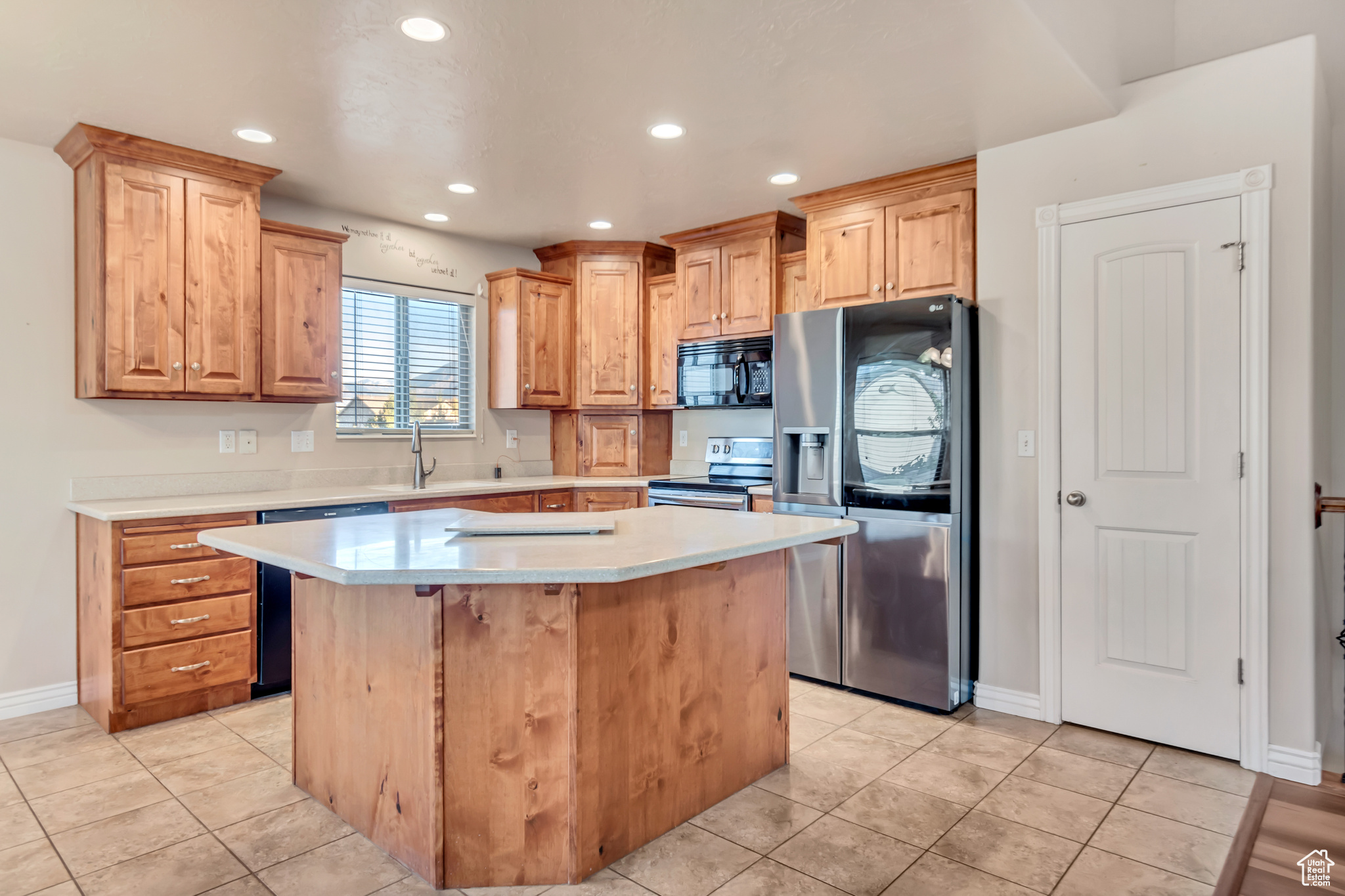 Kitchen with a center island, stainless steel appliances, sink, and light tile patterned floors