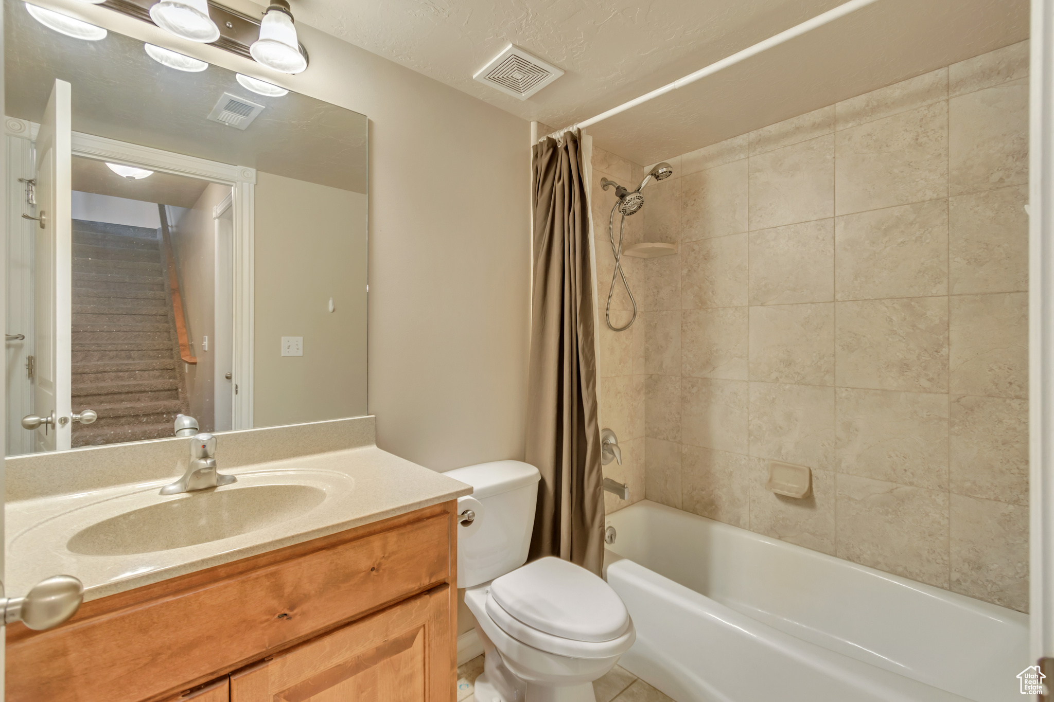 Full bathroom with tile patterned floors, toilet, shower / tub combo with curtain, and vanity