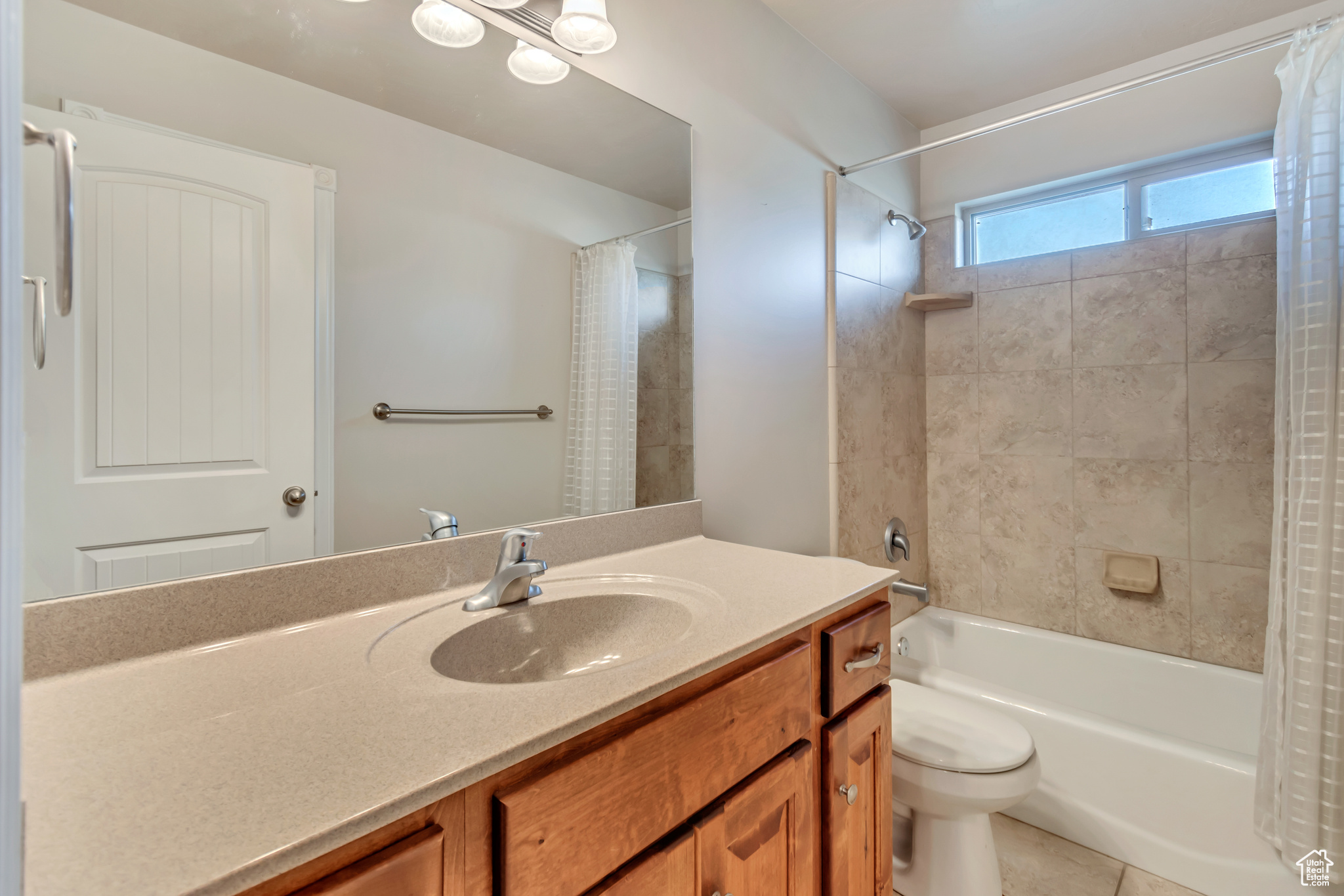 Full bathroom with shower / bath combo with shower curtain, tile patterned floors, toilet, and vanity