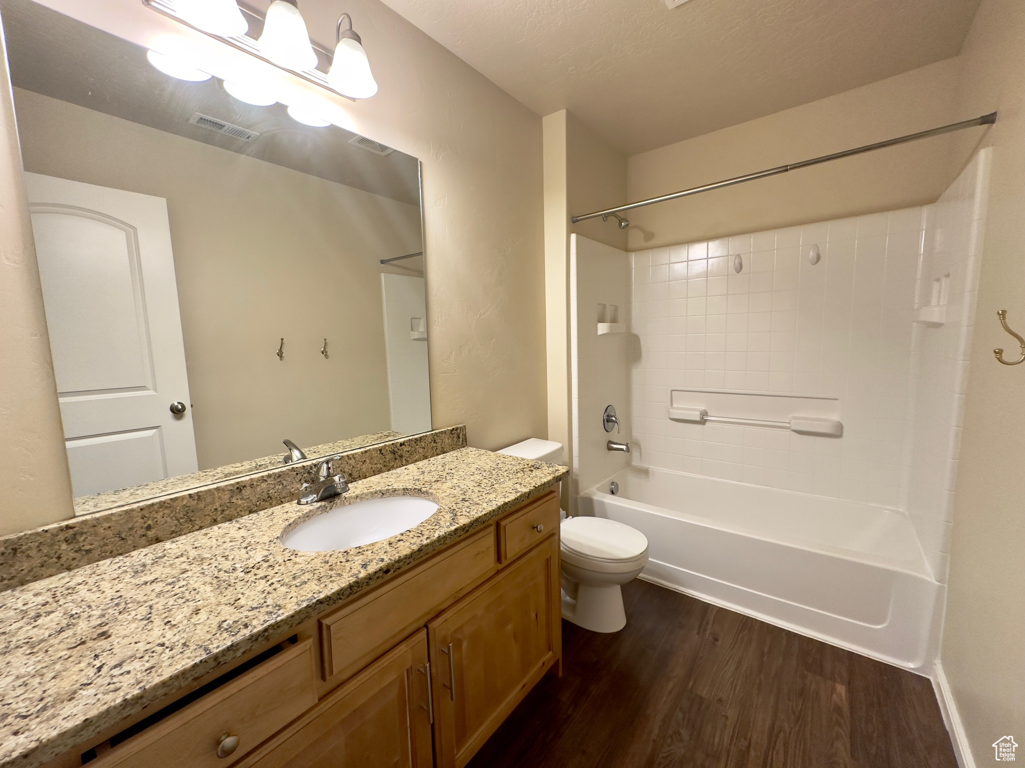 Full bathroom featuring hardwood flooring, toilet, tiled shower / bath combo, and vanity