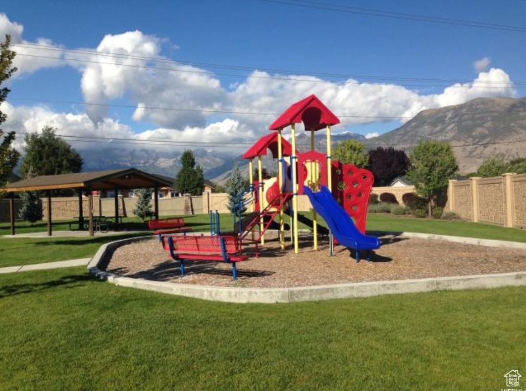 View of playground featuring a mountain view, a yard, and a pavilion