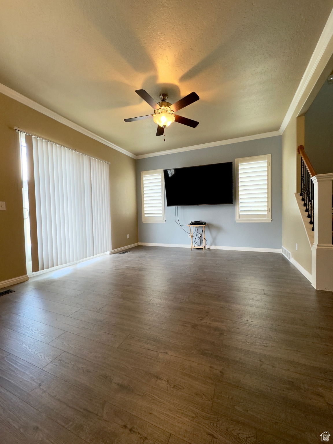 Main floor family room with crown molding, ceiling fan, dark hardwood floors & sliding glass door to gated backyard