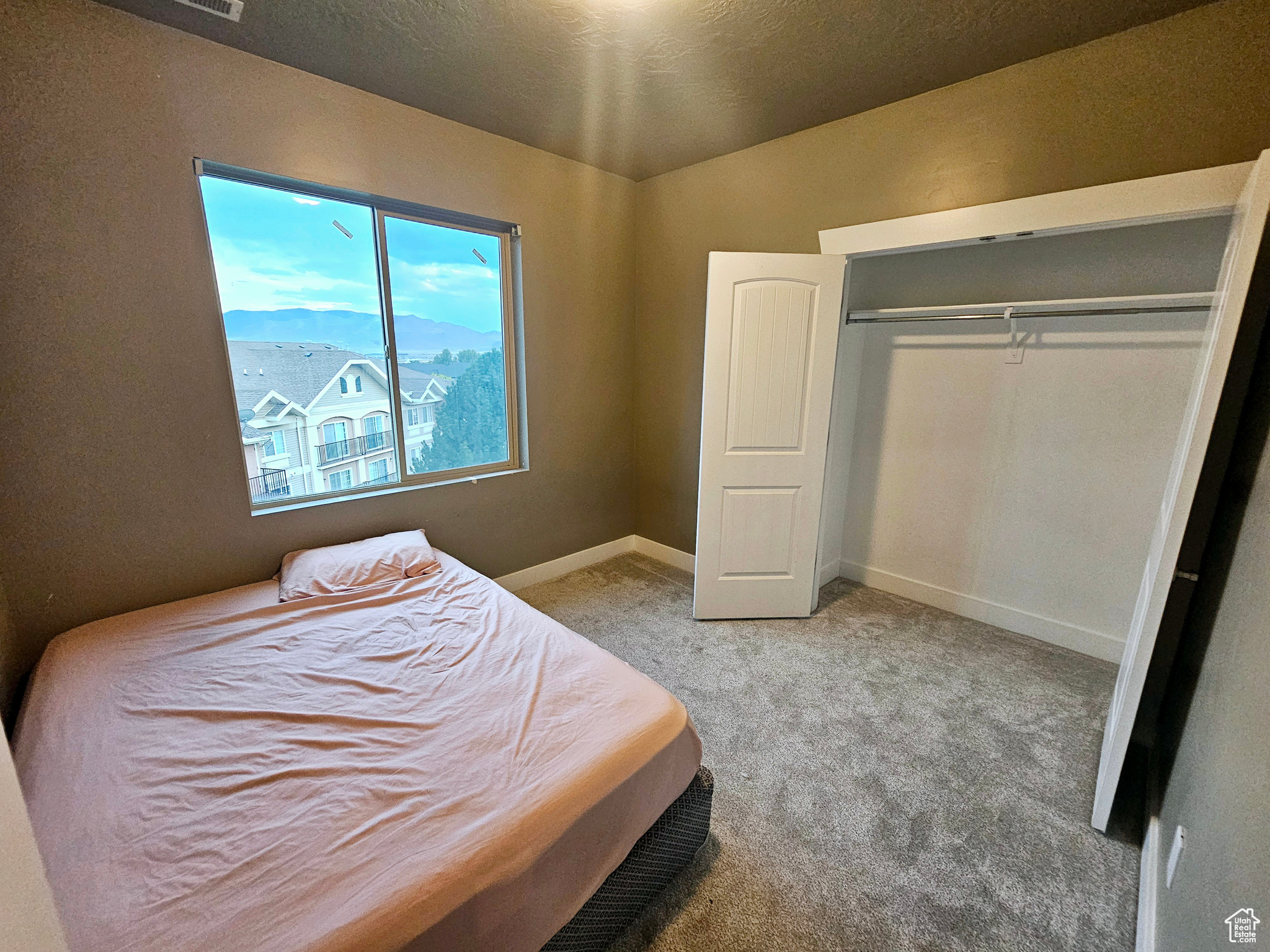 Carpeted bedroom with a closet and a textured ceiling