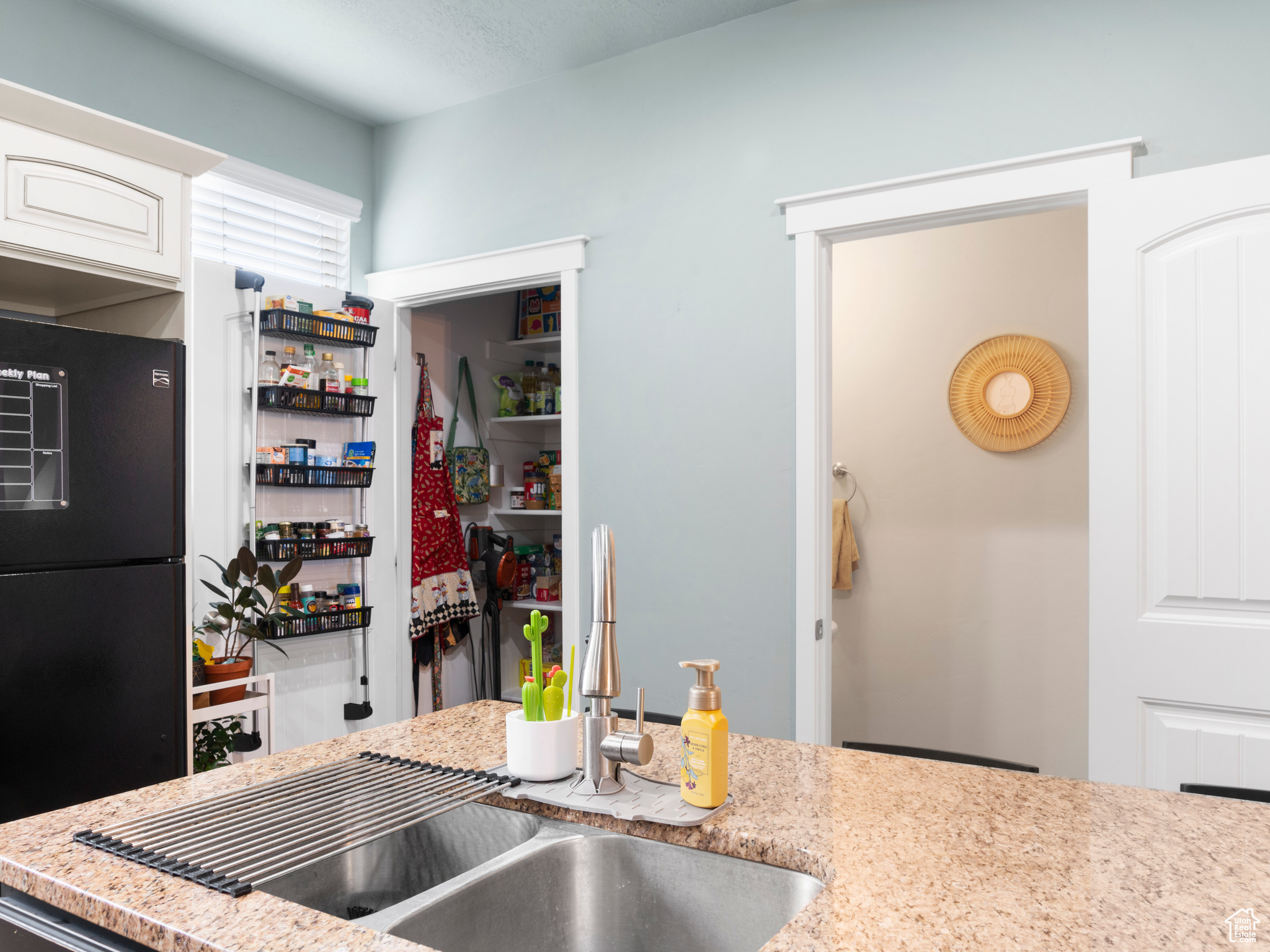 Kitchen with sink, white cabinets, and black fridge