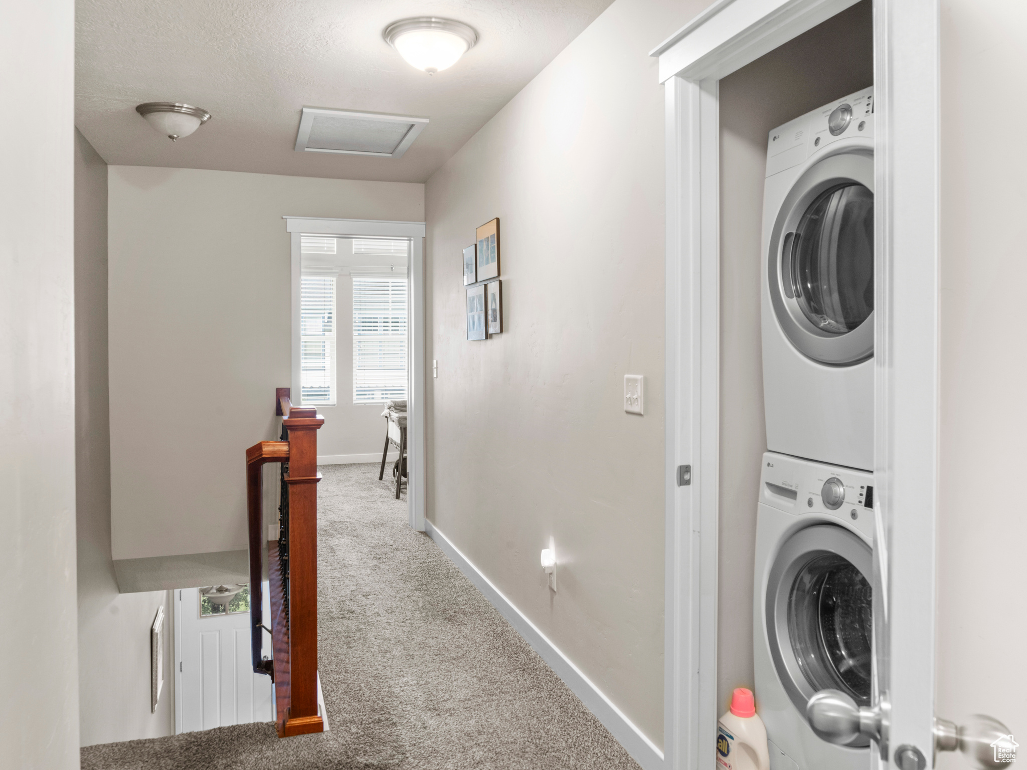 Clothes washing area featuring stacked washer / dryer and carpet floors