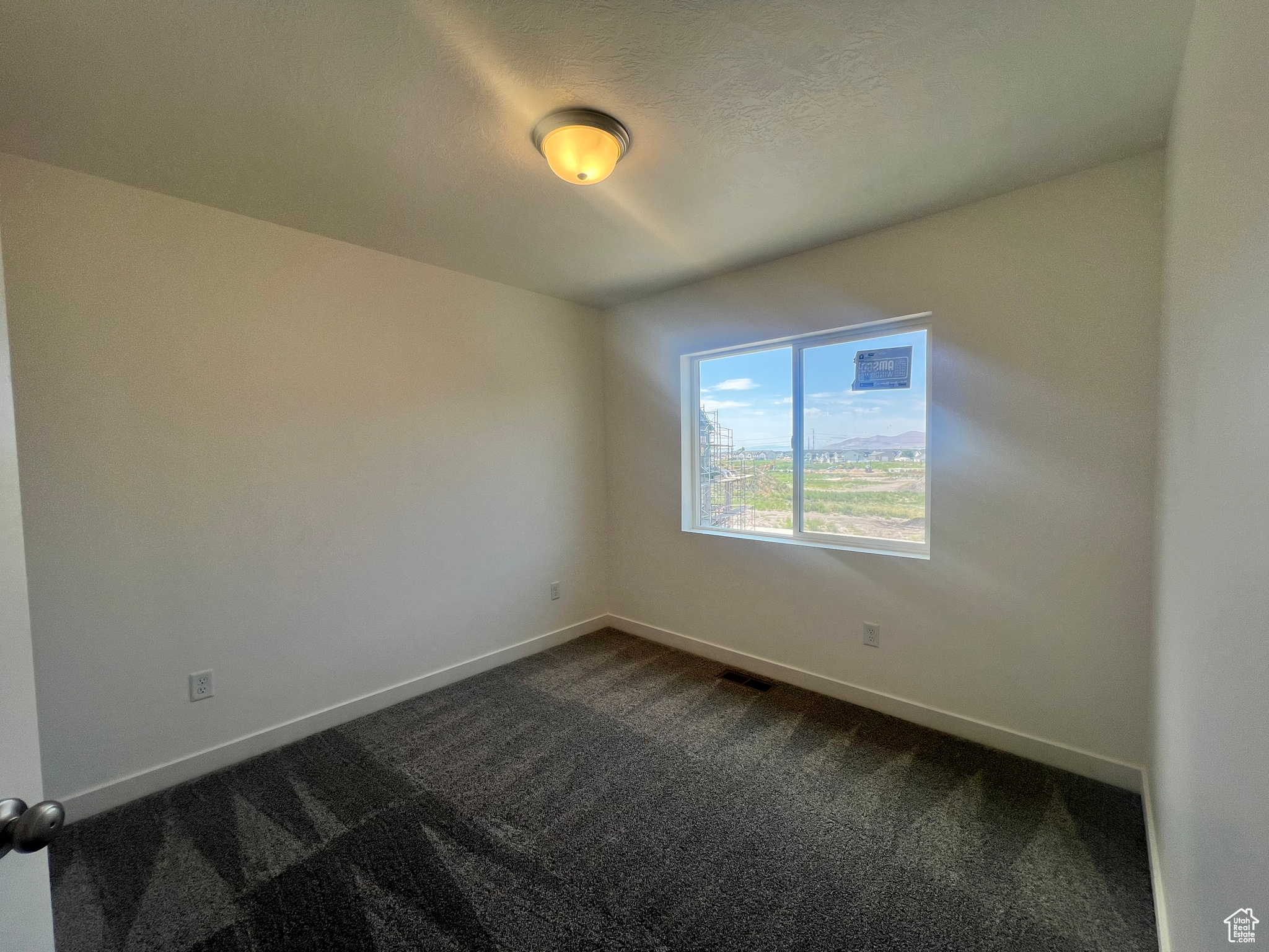 Carpeted spare room featuring a textured ceiling