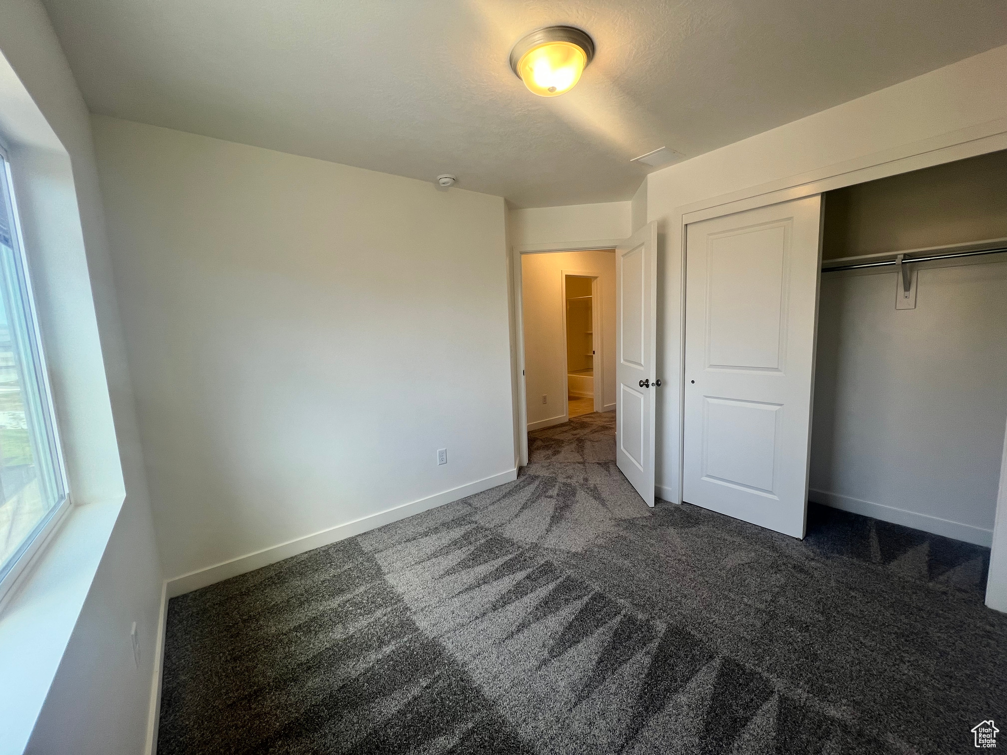 Unfurnished bedroom featuring dark colored carpet and a closet