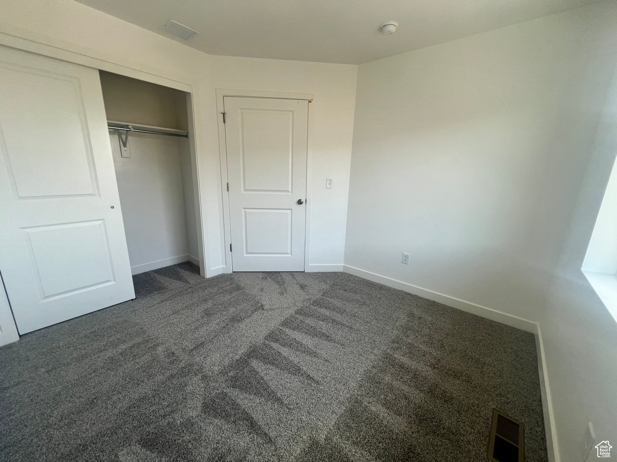 Unfurnished bedroom featuring dark colored carpet and a closet