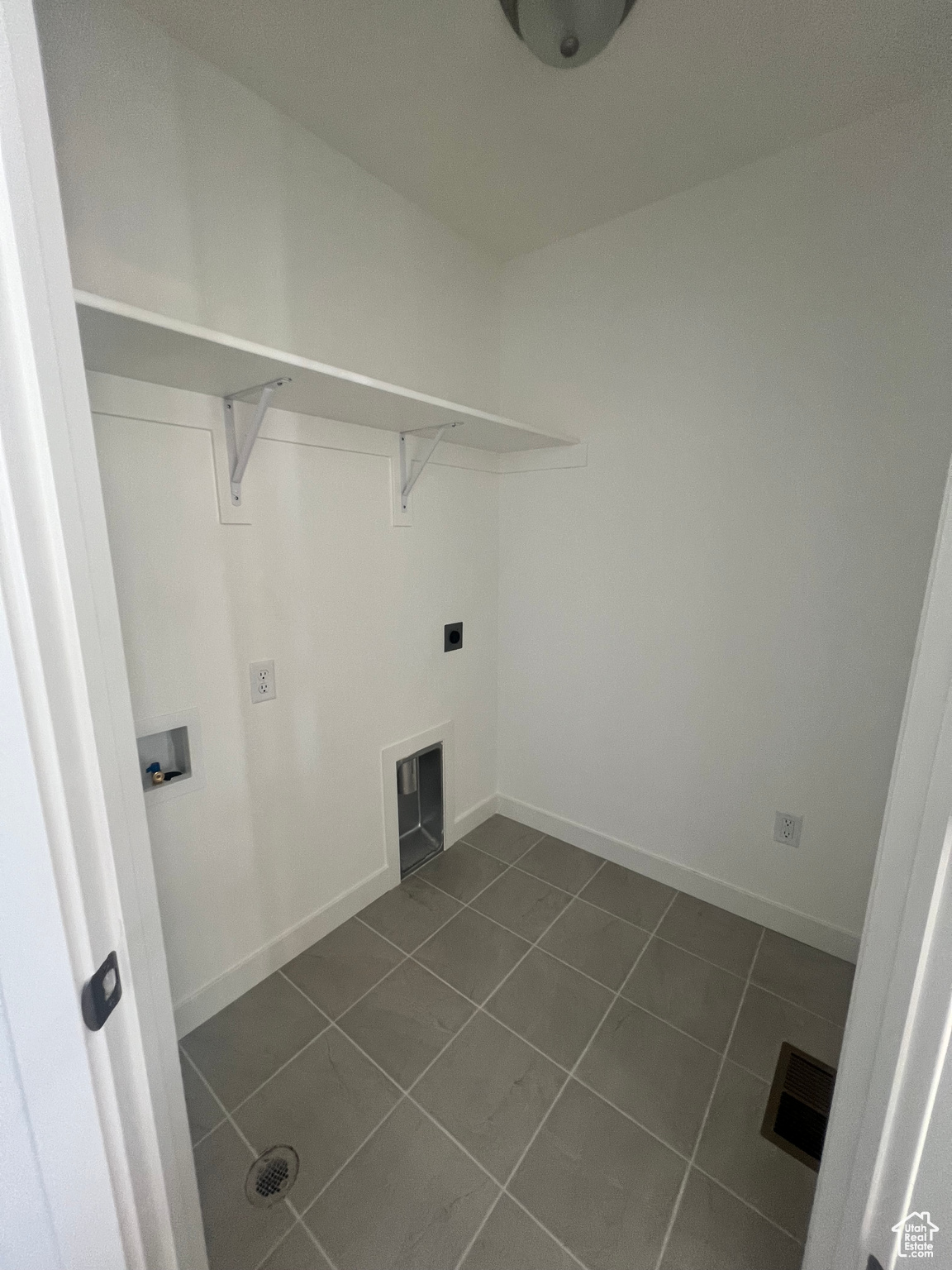 Laundry room with washer hookup, dark tile patterned flooring, and electric dryer hookup