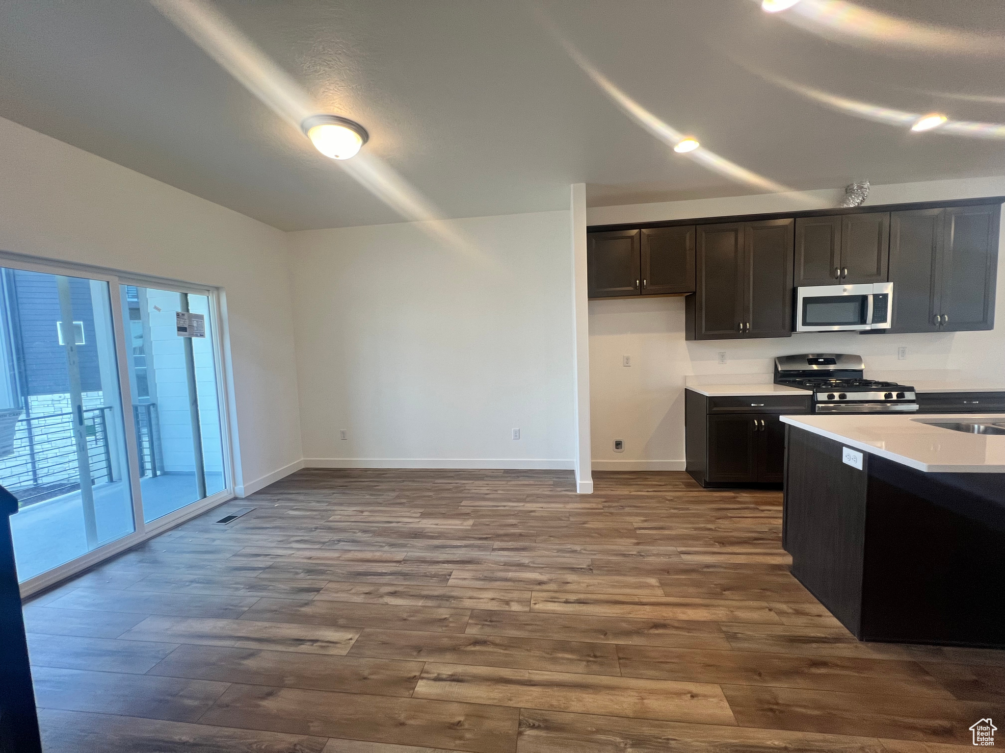 Kitchen with stainless steel appliances, dark brown cabinetry, and wood-type flooring