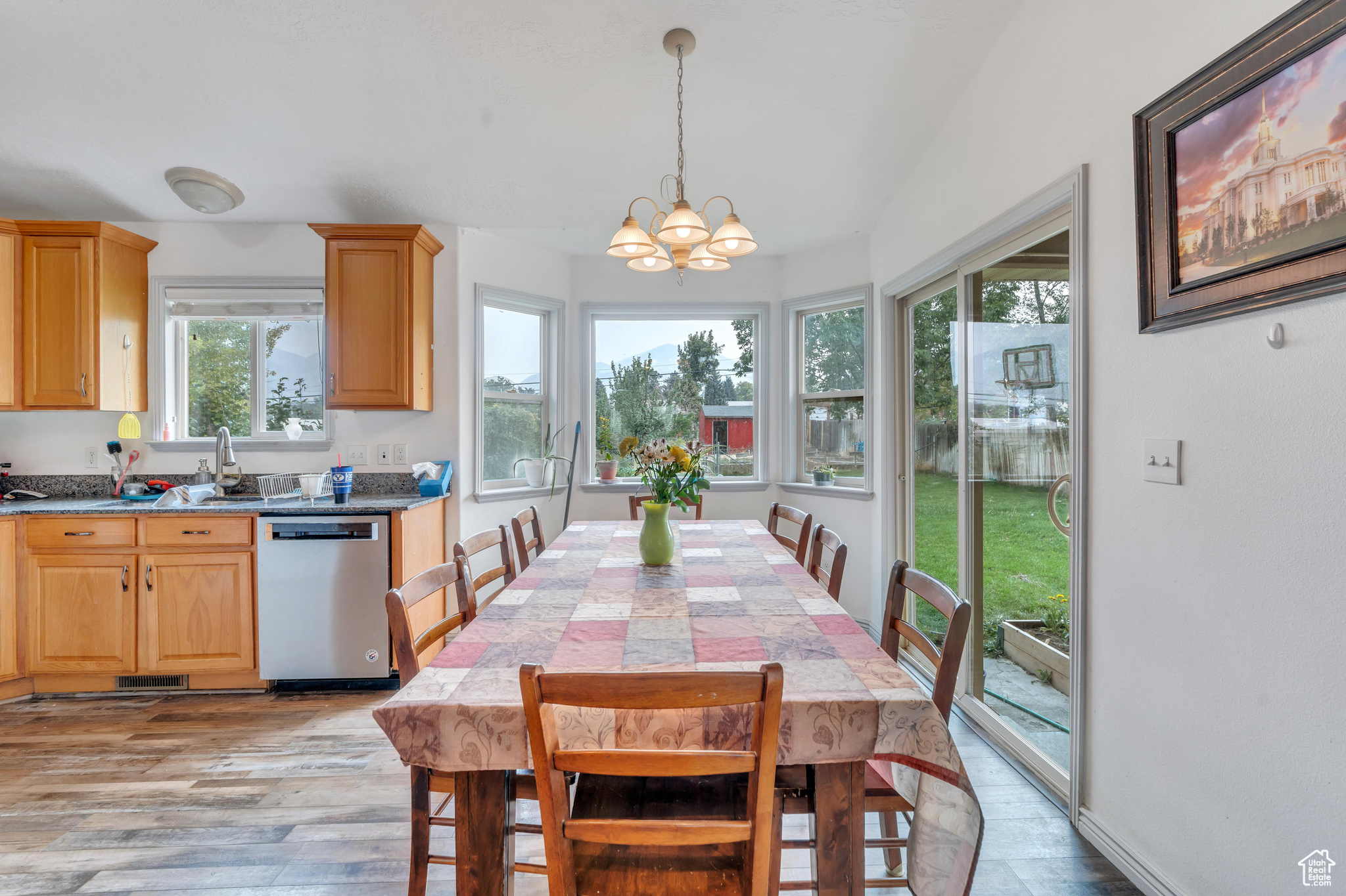 Dining area with a healthy amount of sunlight, a notable chandelier, sink, and light wood-type flooring