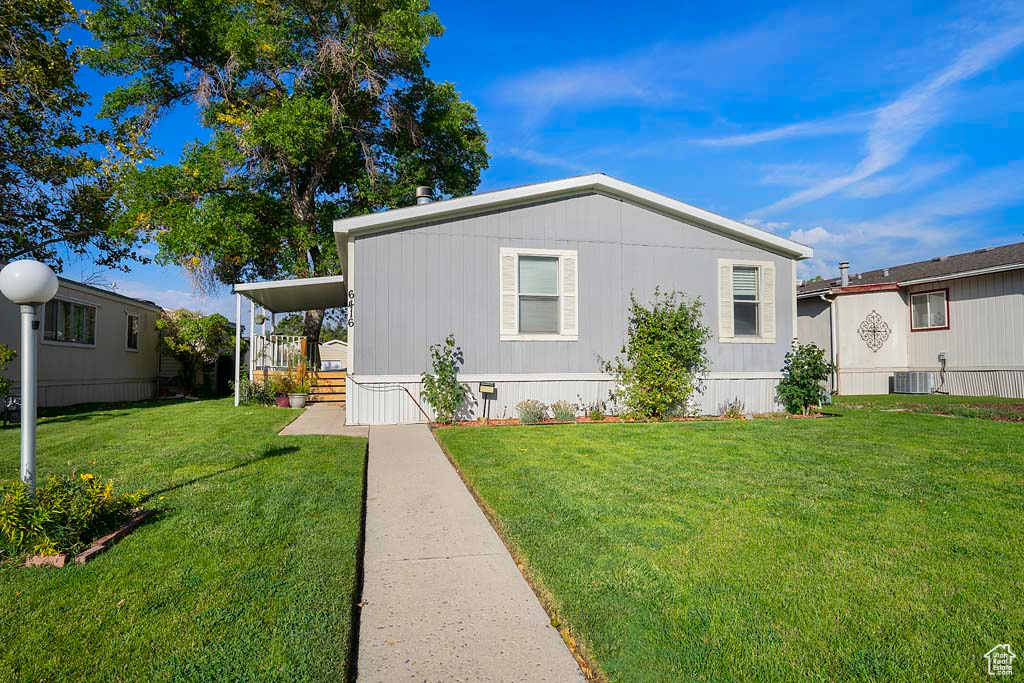 Manufactured / mobile home featuring cooling unit and a front lawn