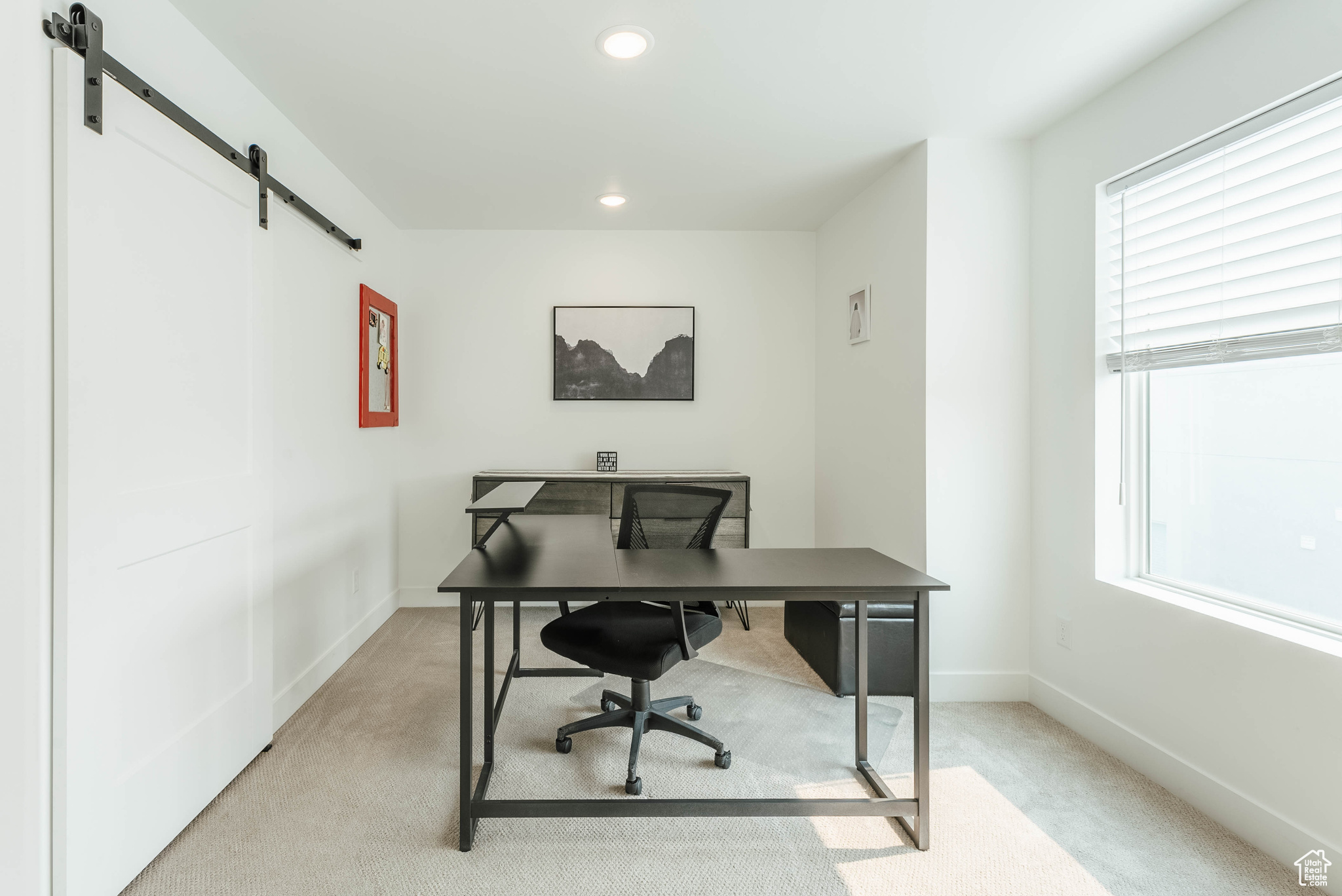 Carpeted office featuring a healthy amount of sunlight and a barn door