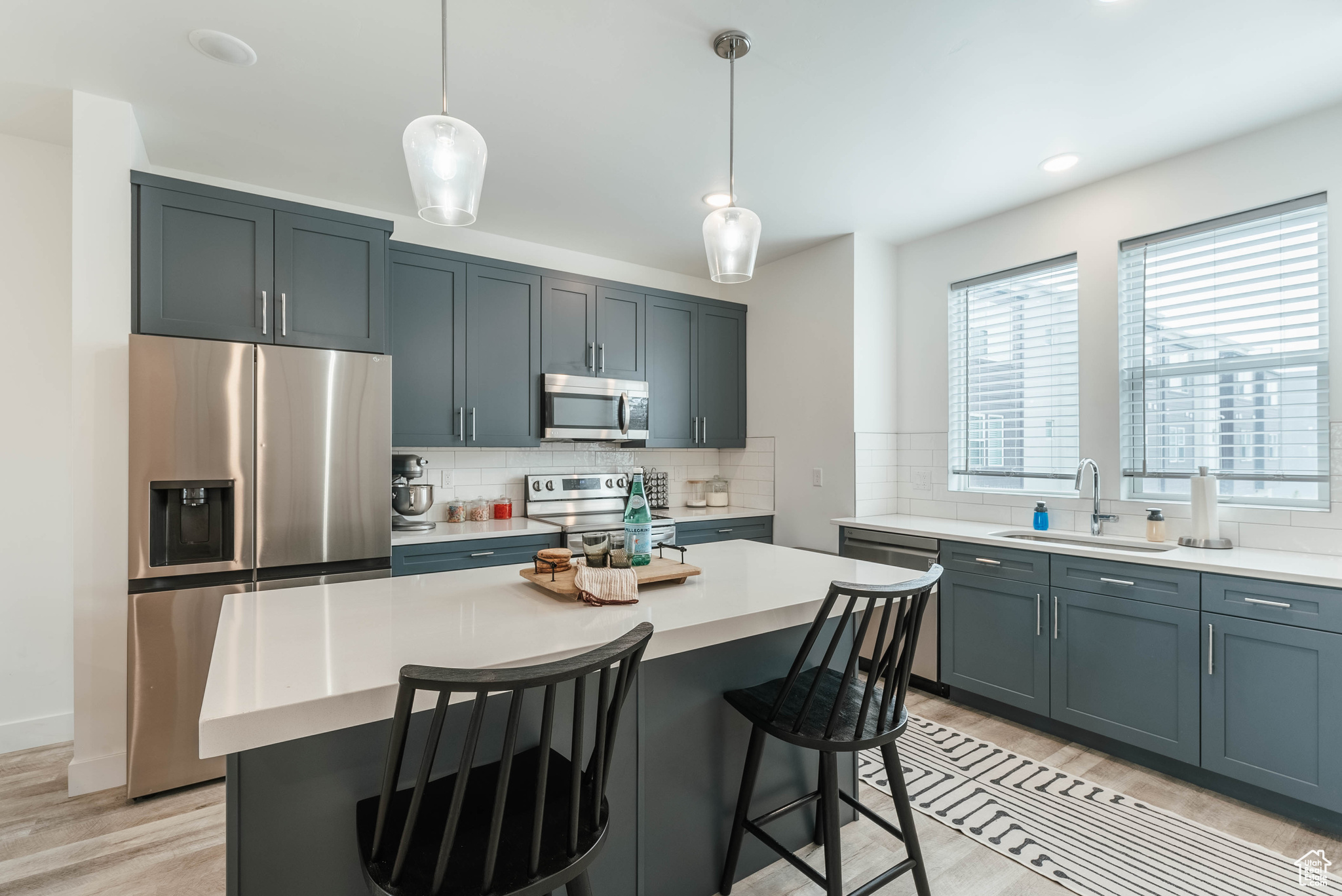 Kitchen with hanging light fixtures, stainless steel appliances, sink, and a kitchen island