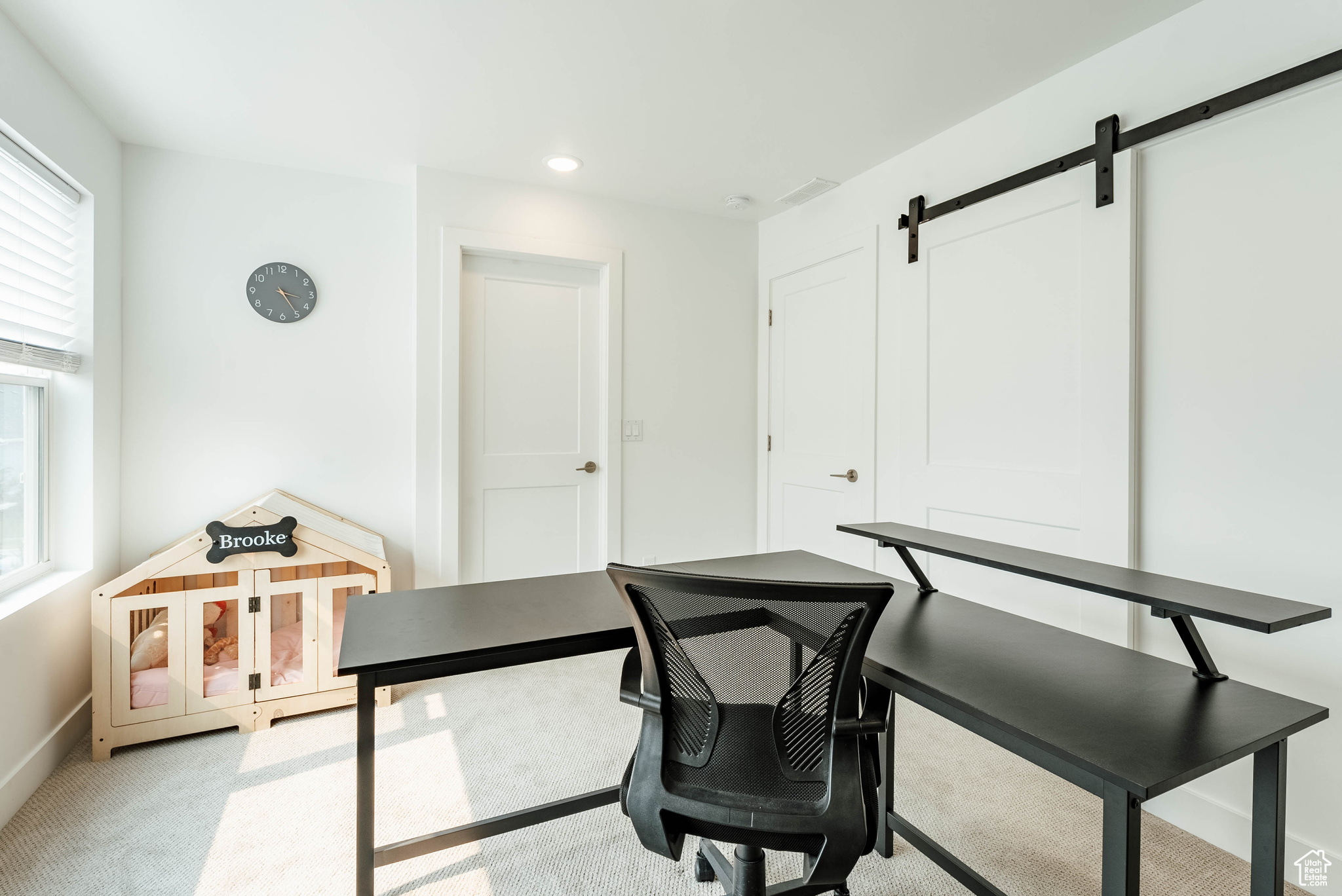 Office area with a barn door and light colored carpet