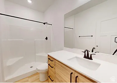 Bathroom featuring a shower, toilet, and vanity