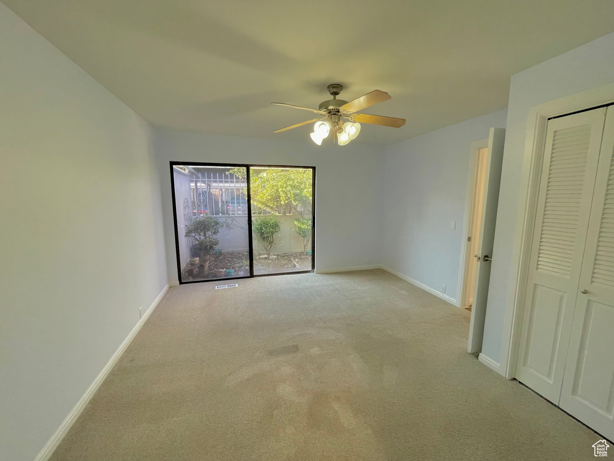 Unfurnished bedroom with ceiling fan and light carpet