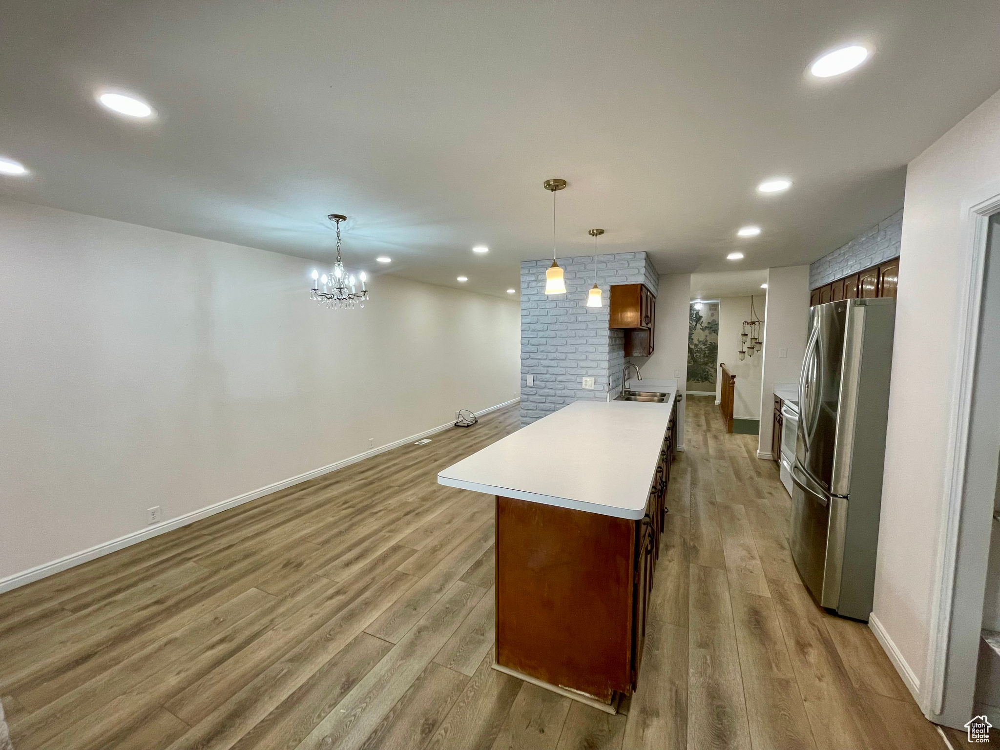 Kitchen featuring sink, pendant lighting, a chandelier, light hardwood / wood-style floors, and stainless steel refrigerator