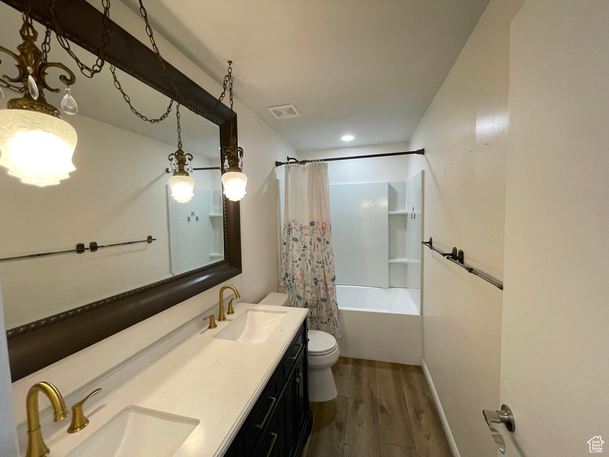 Full bathroom with wood-type flooring, vanity, shower / tub combo, and toilet