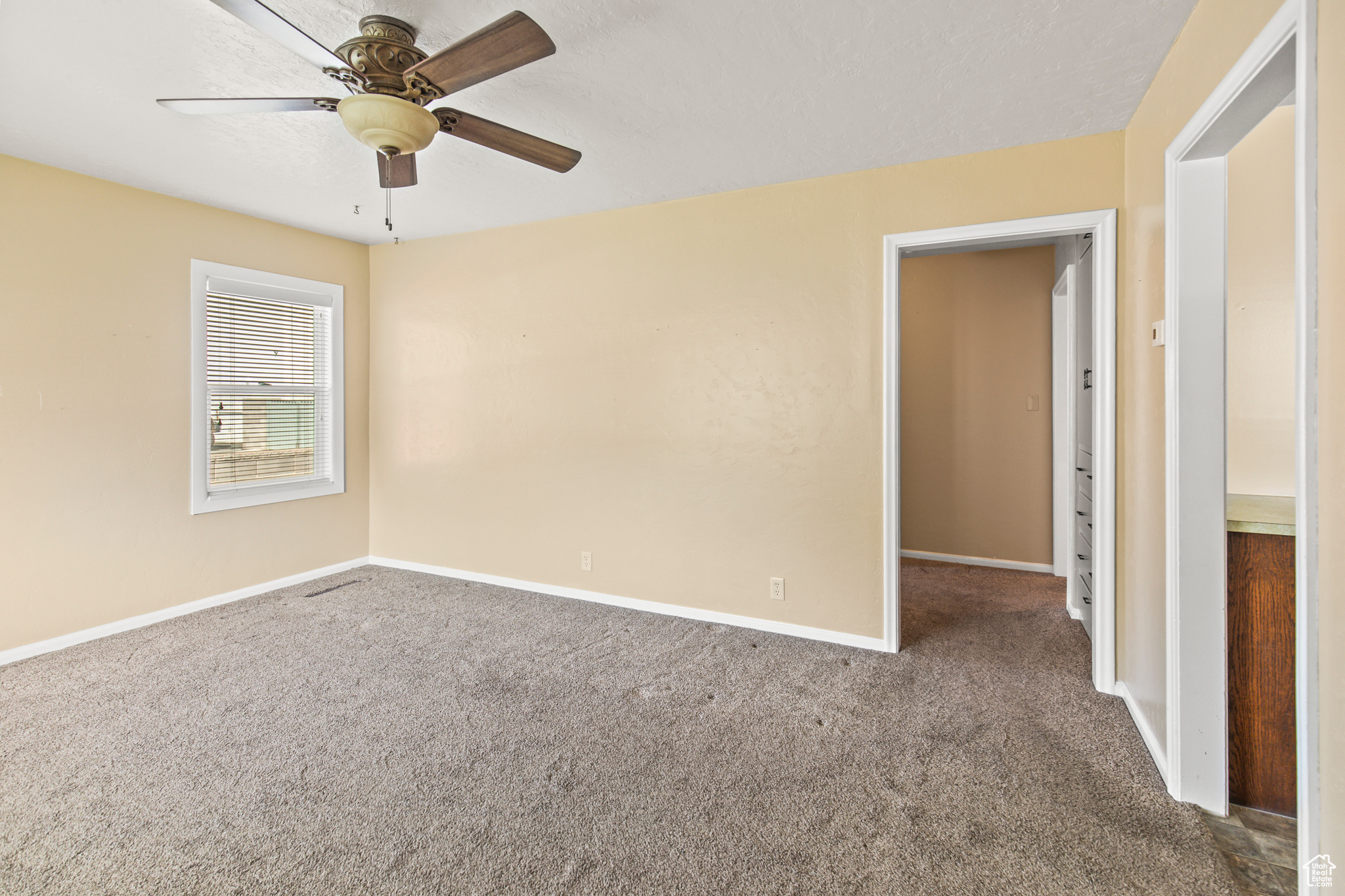 Carpeted spare room featuring ceiling fan