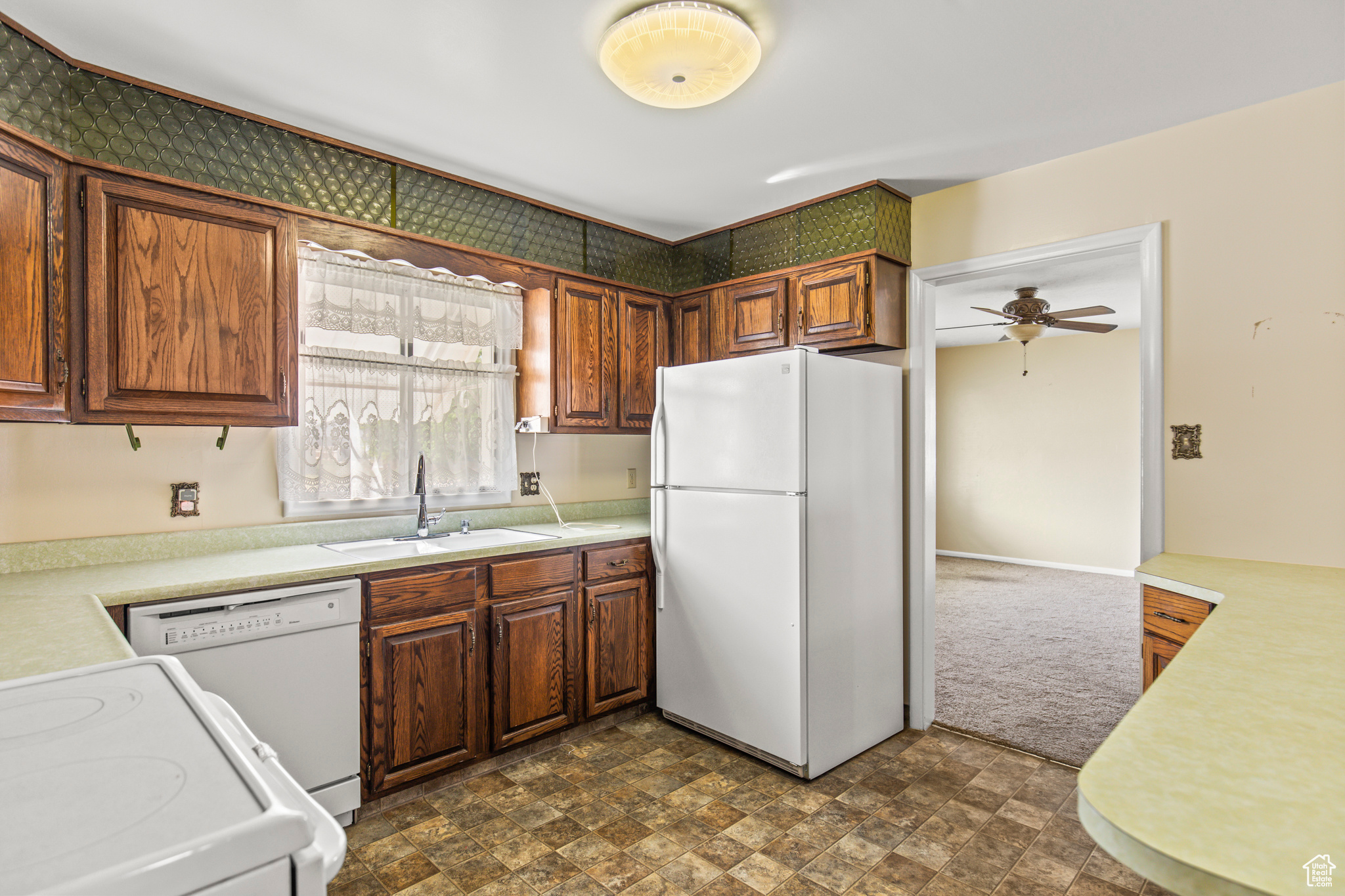 Kitchen featuring ceiling fan, sink, and white appliances