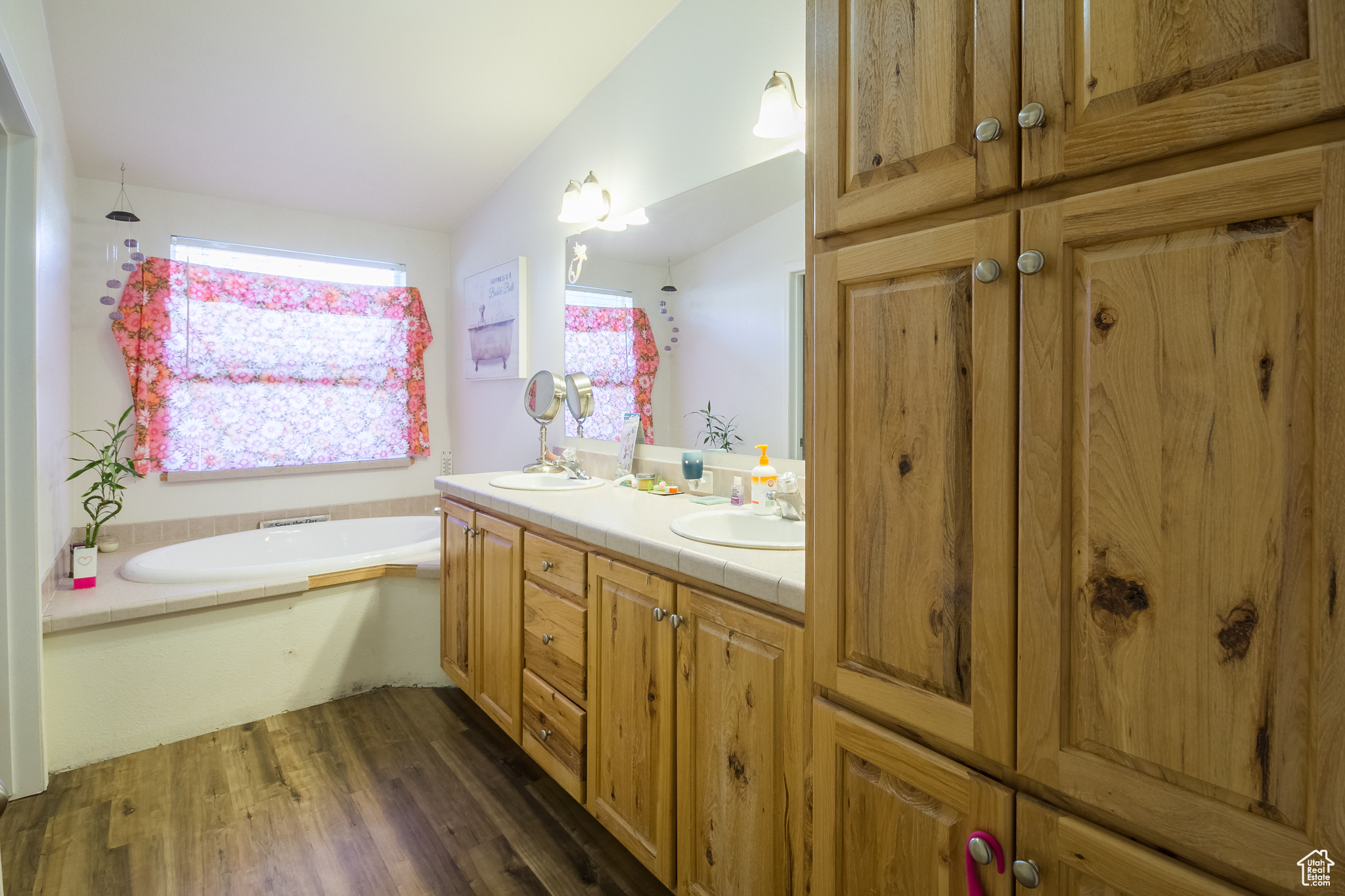 Bathroom with hardwood / wood-style floors, vanity, a bathing tub, and vaulted ceiling