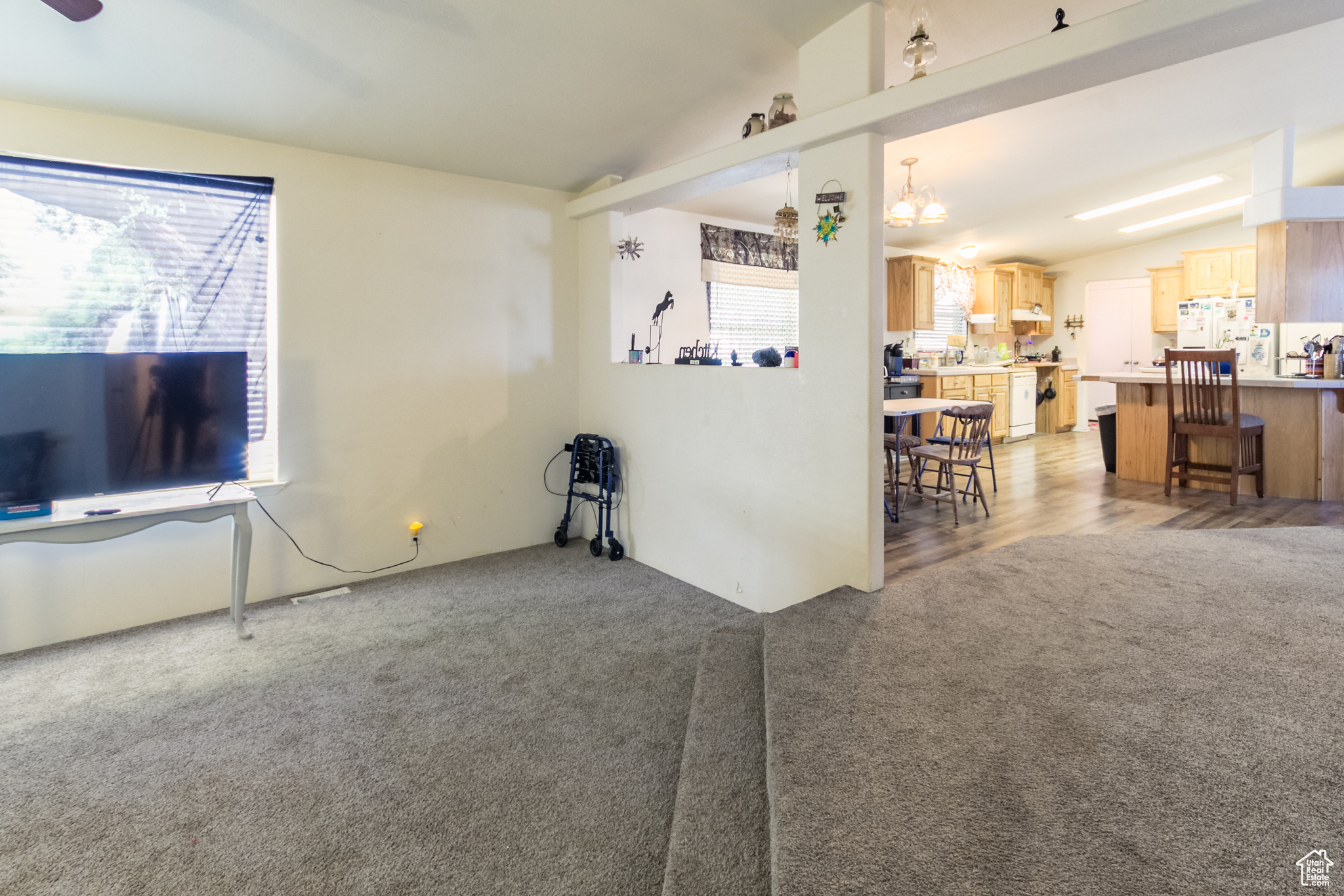 Carpeted living room featuring plenty of natural light, lofted ceiling, and a notable chandelier