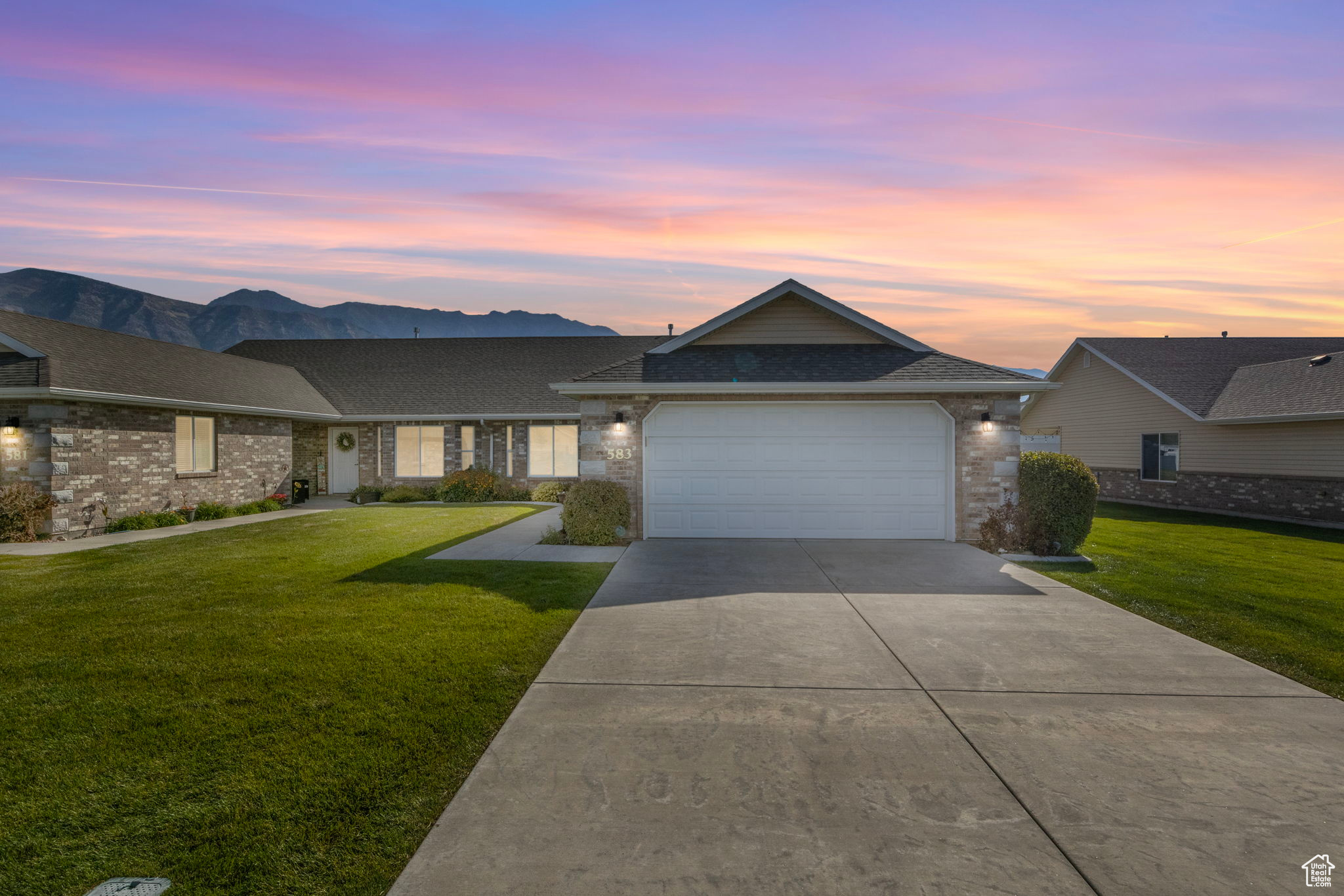 Ranch-style home featuring a mountain view, a yard, and a garage