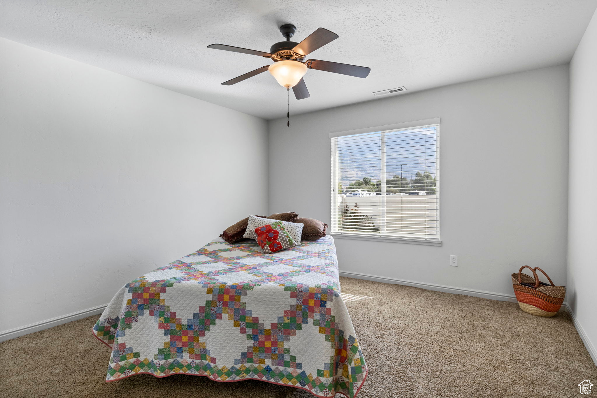 Carpeted bedroom with a textured ceiling and ceiling fan