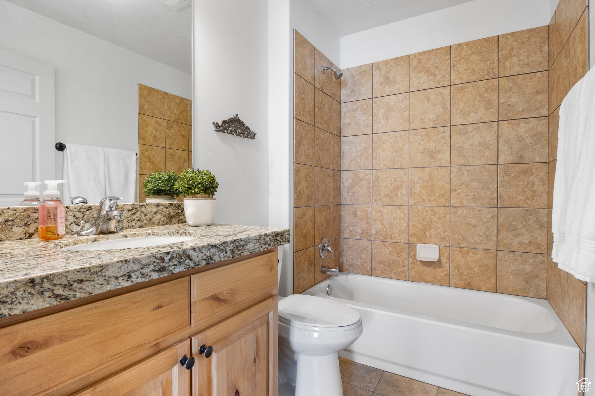 Full bathroom featuring tiled shower / bath combo, vanity, toilet, and tile patterned floors