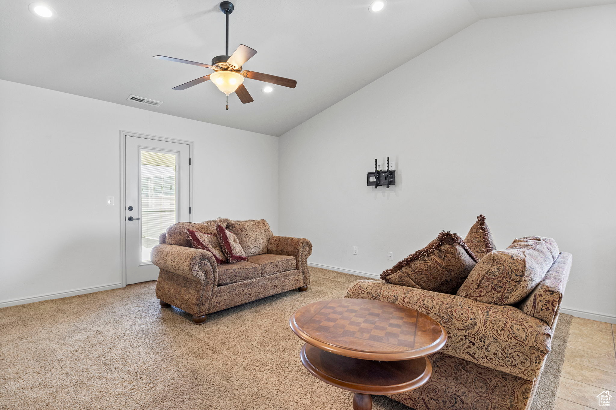 Living room featuring lofted ceiling, light tile patterned flooring, and ceiling fan