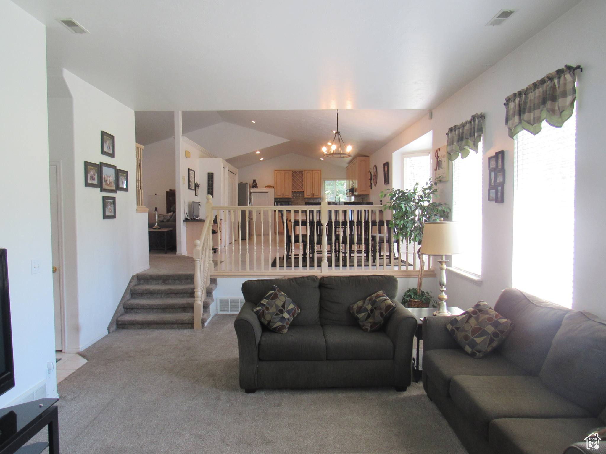 Carpeted living room featuring lofted ceiling and a notable chandelier