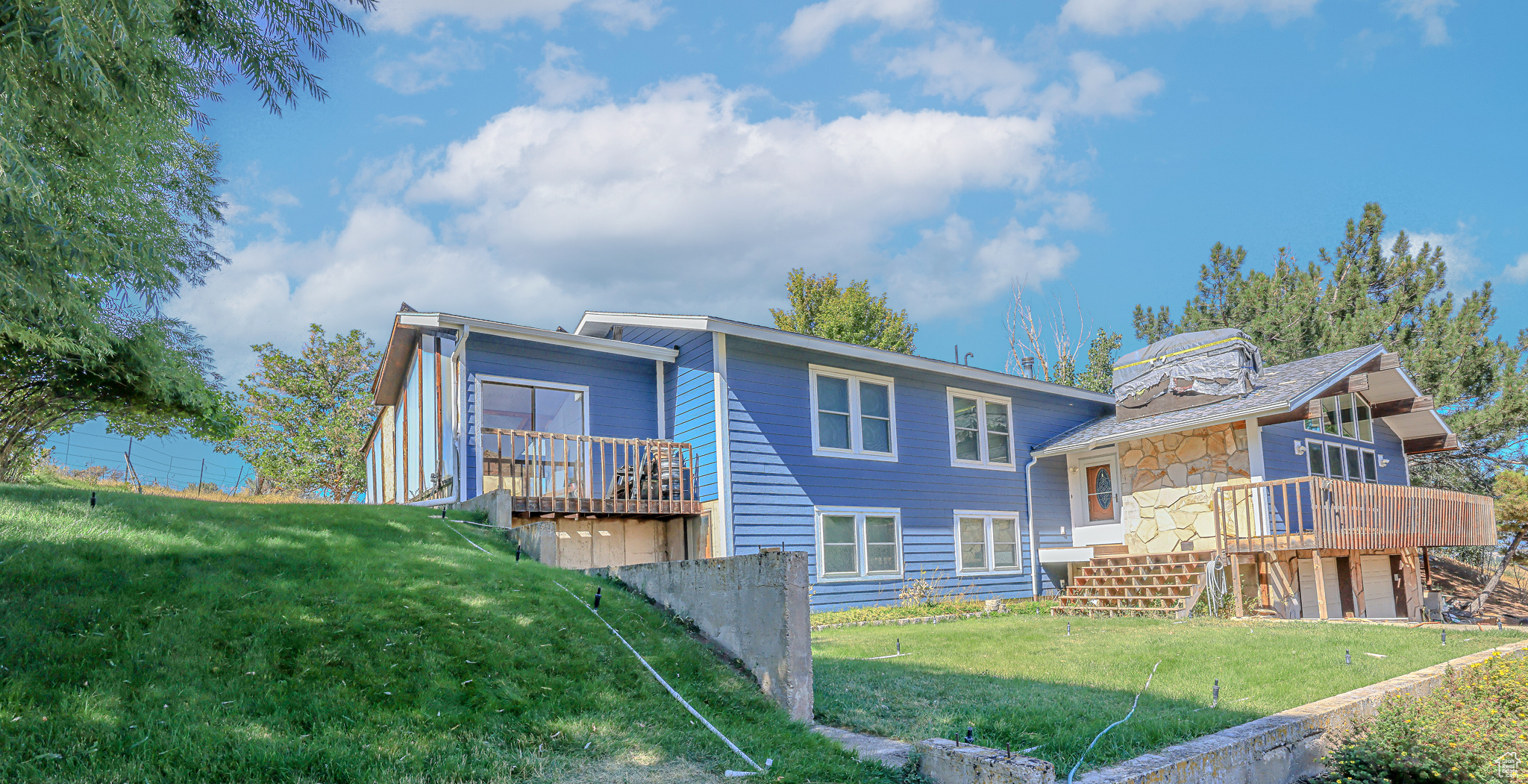 View of front facade with a wooden deck and a front lawn