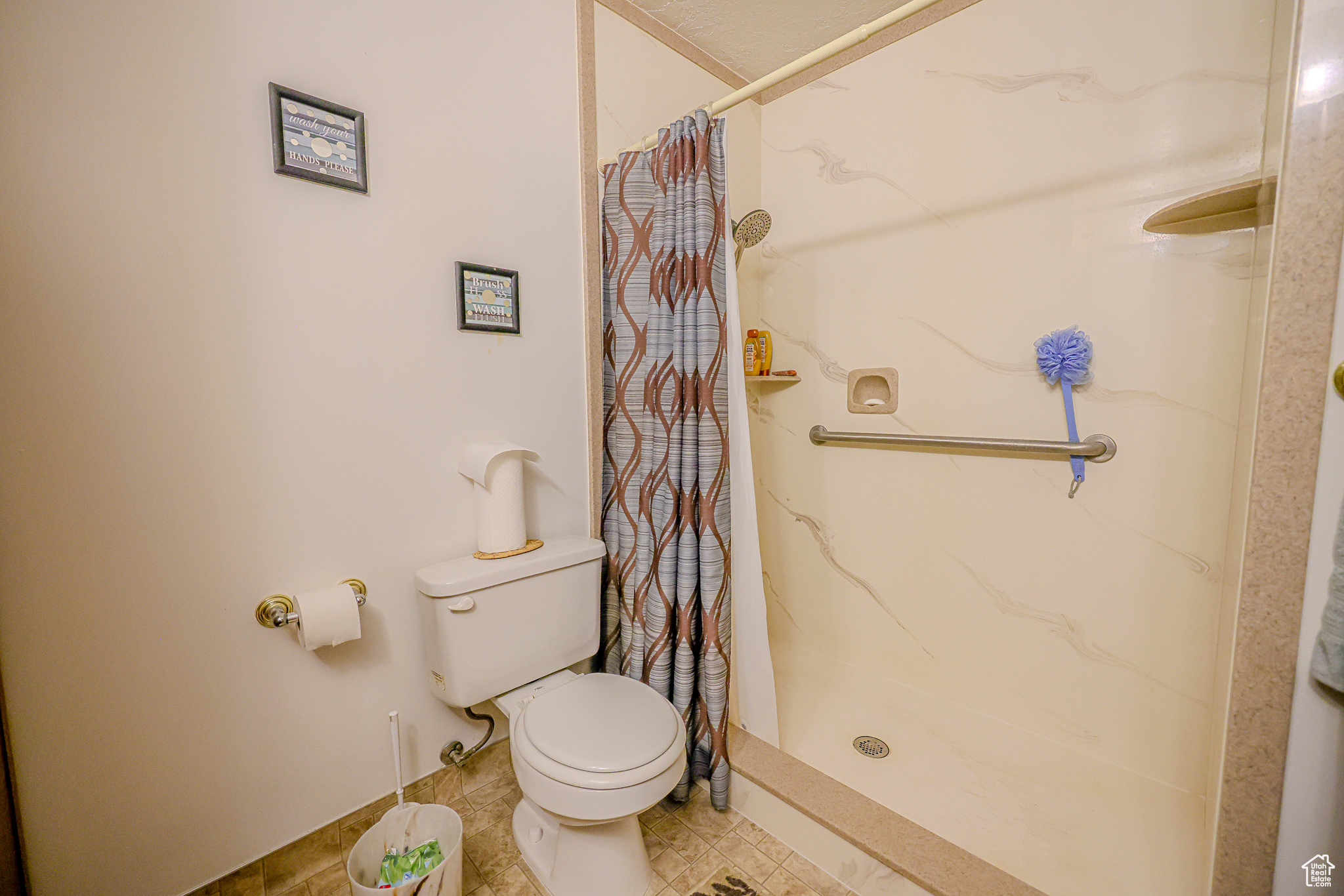 Bathroom featuring toilet, a shower with curtain, and tile patterned floors