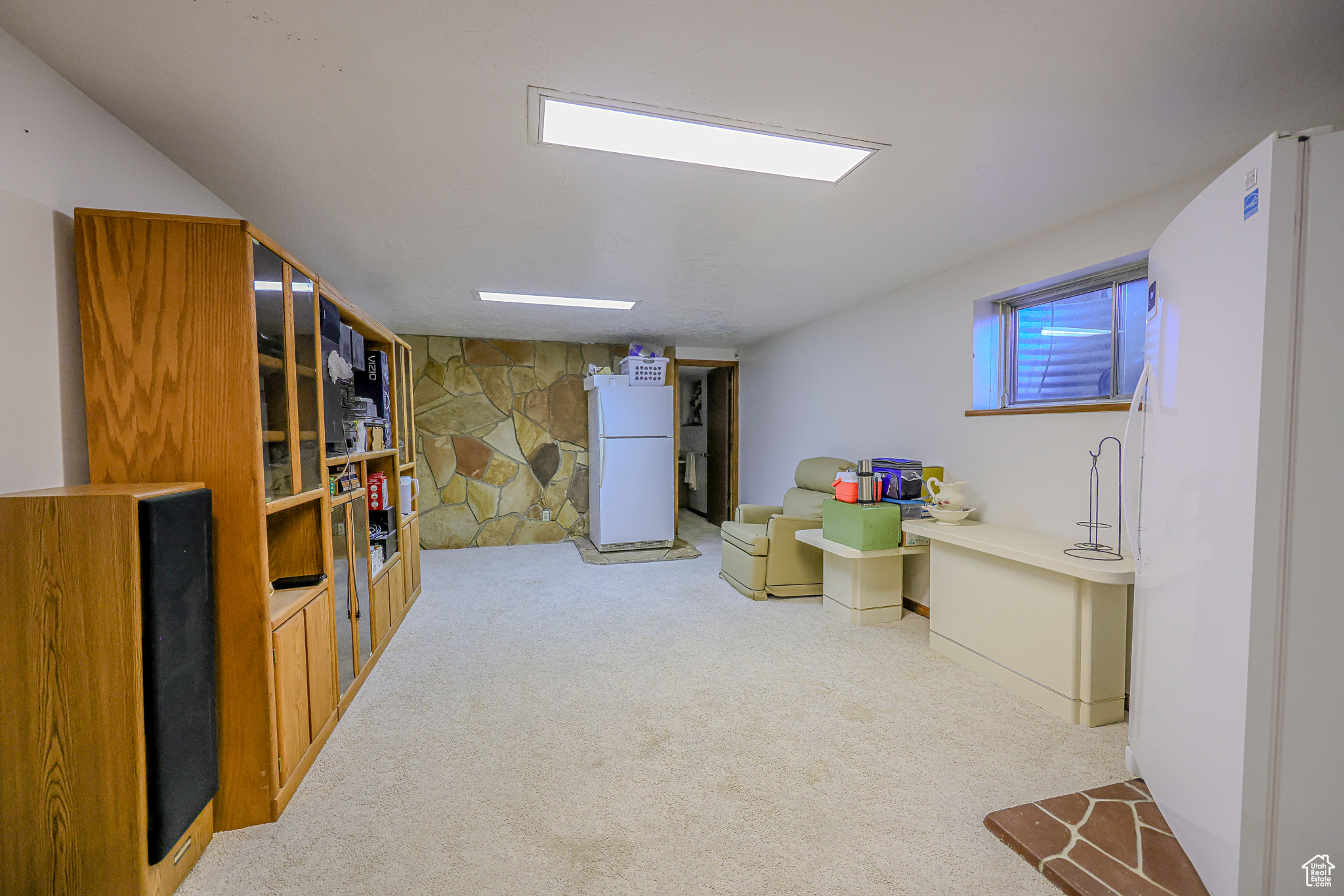 Basement featuring white refrigerator and light carpet