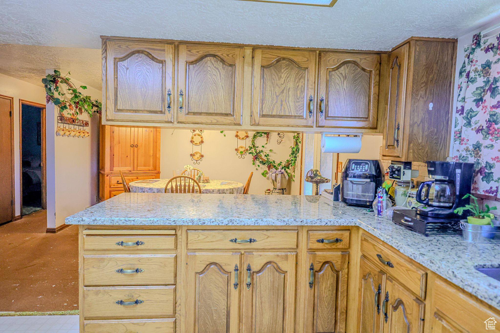 Kitchen with light stone countertops, kitchen peninsula, and a textured ceiling