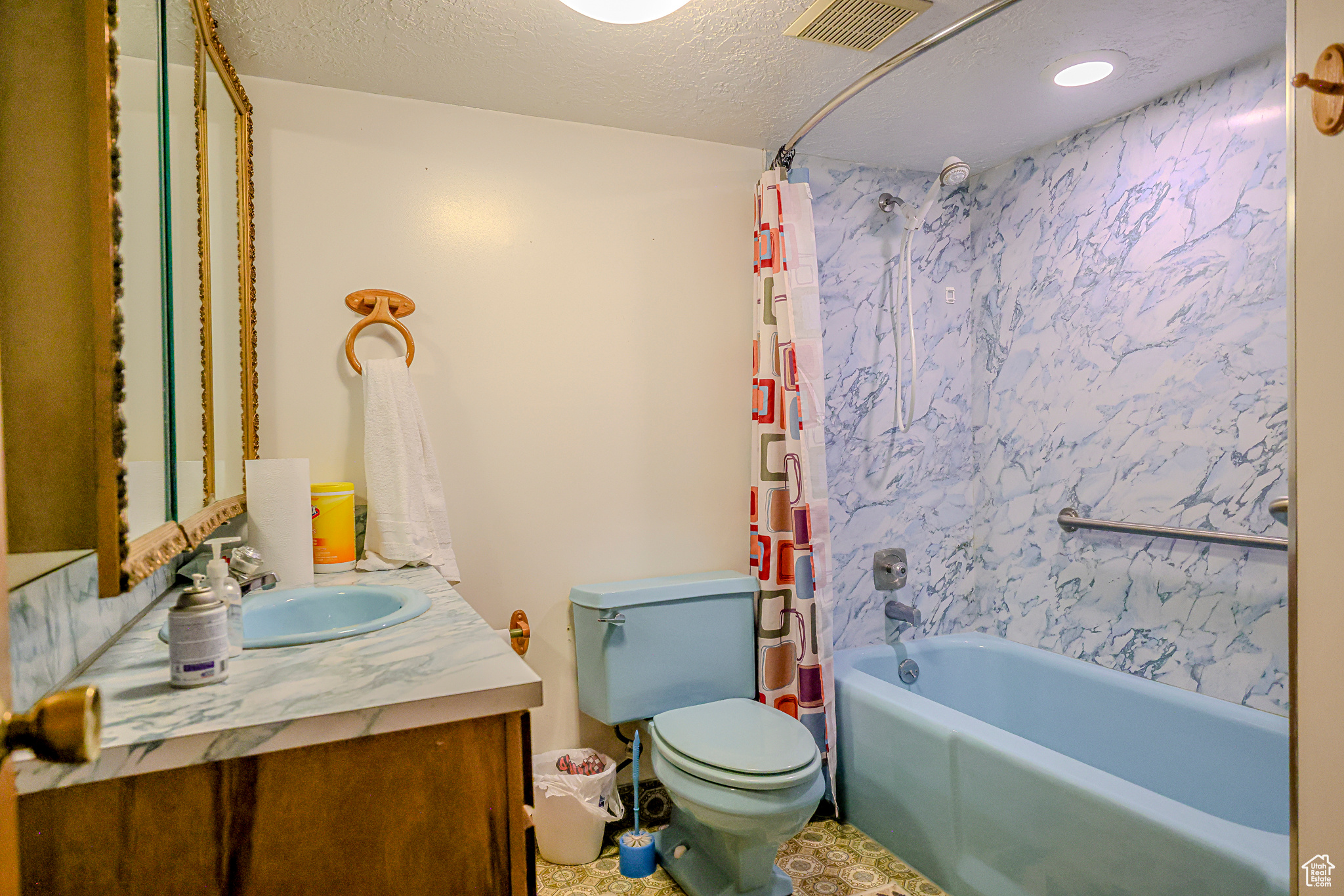 Full bathroom featuring vanity, toilet, a textured ceiling, and shower / bath combo with shower curtain