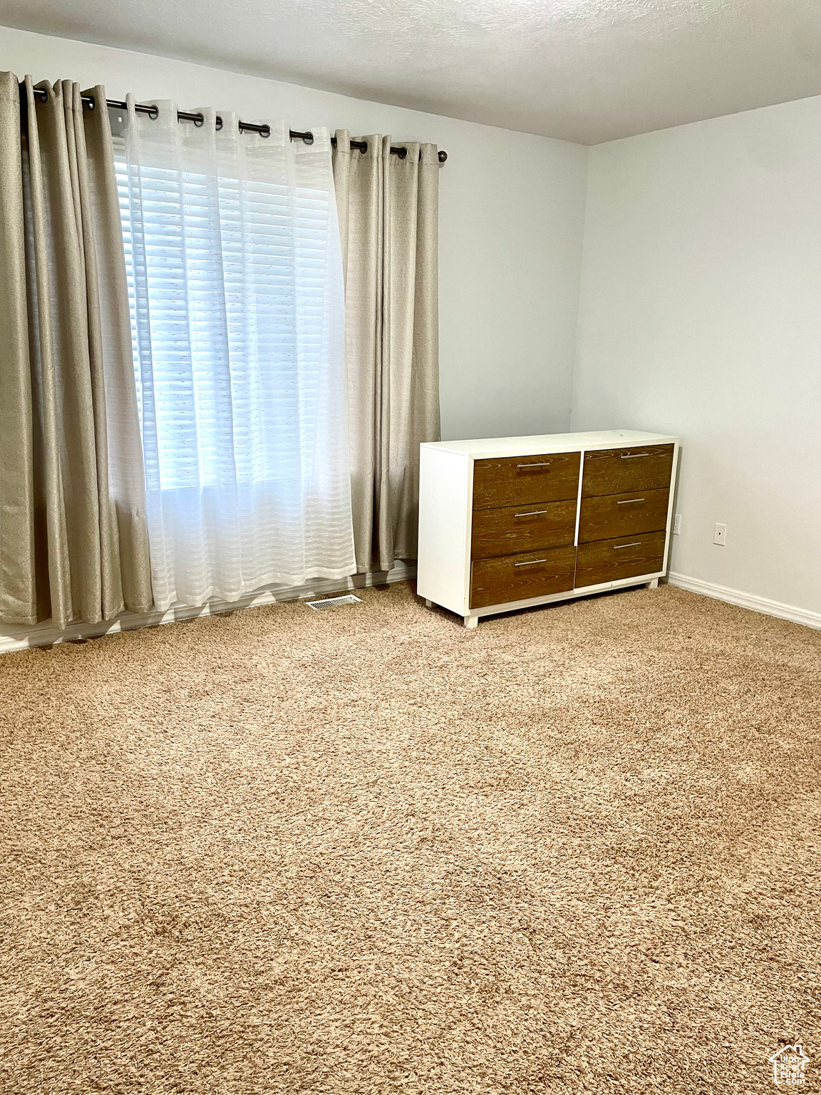 Empty room with a textured ceiling and light colored carpet