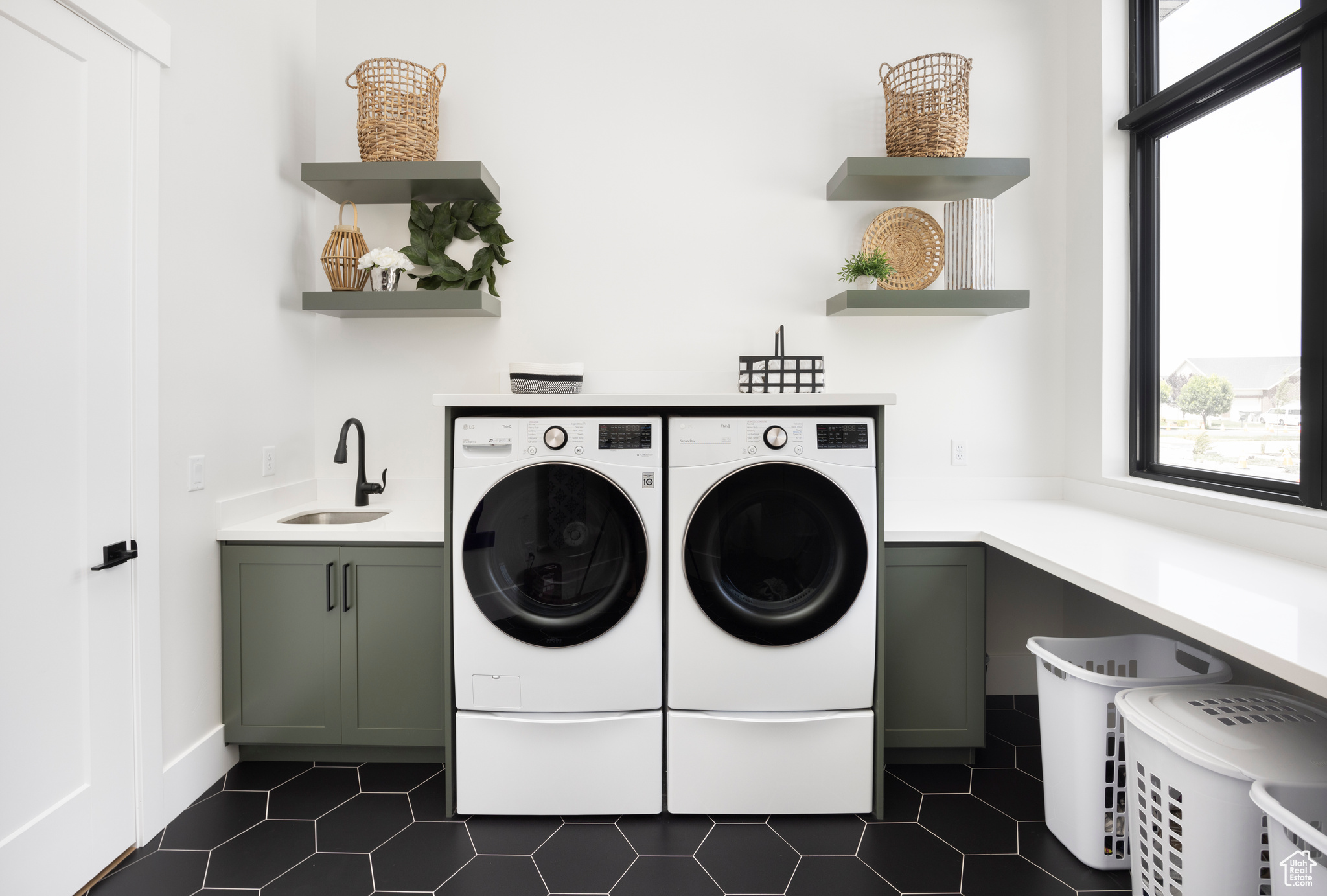 Washroom with cabinets, sink, washing machine and dryer, and dark tile patterned flooring