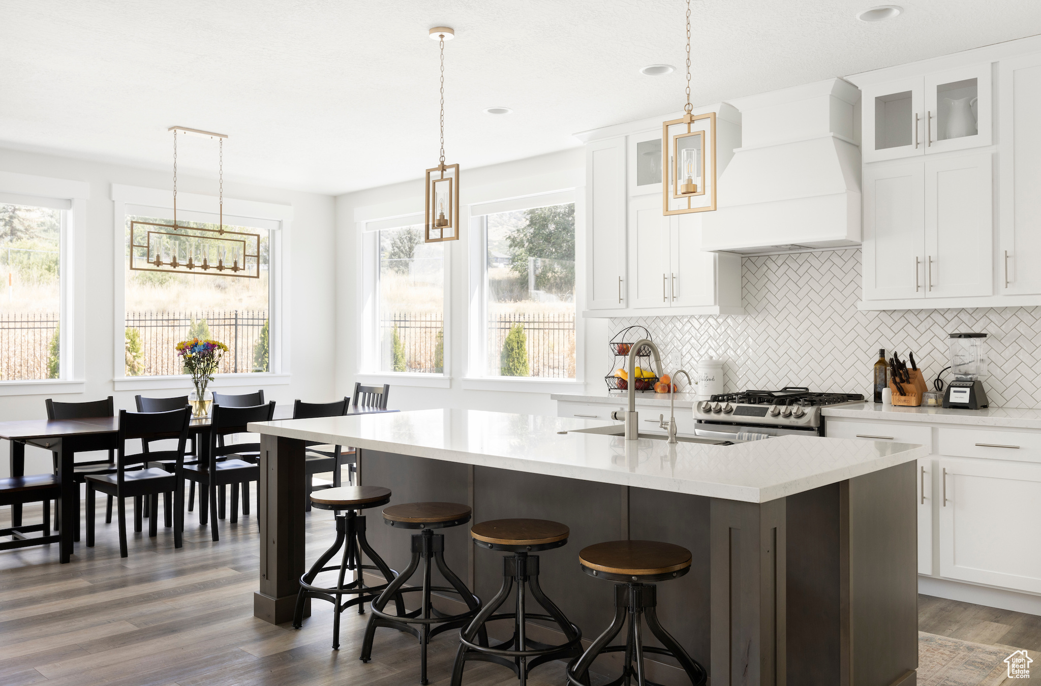 Kitchen with white cabinetry, high end range, dark hardwood / wood-style flooring, hanging light fixtures, and custom range hood