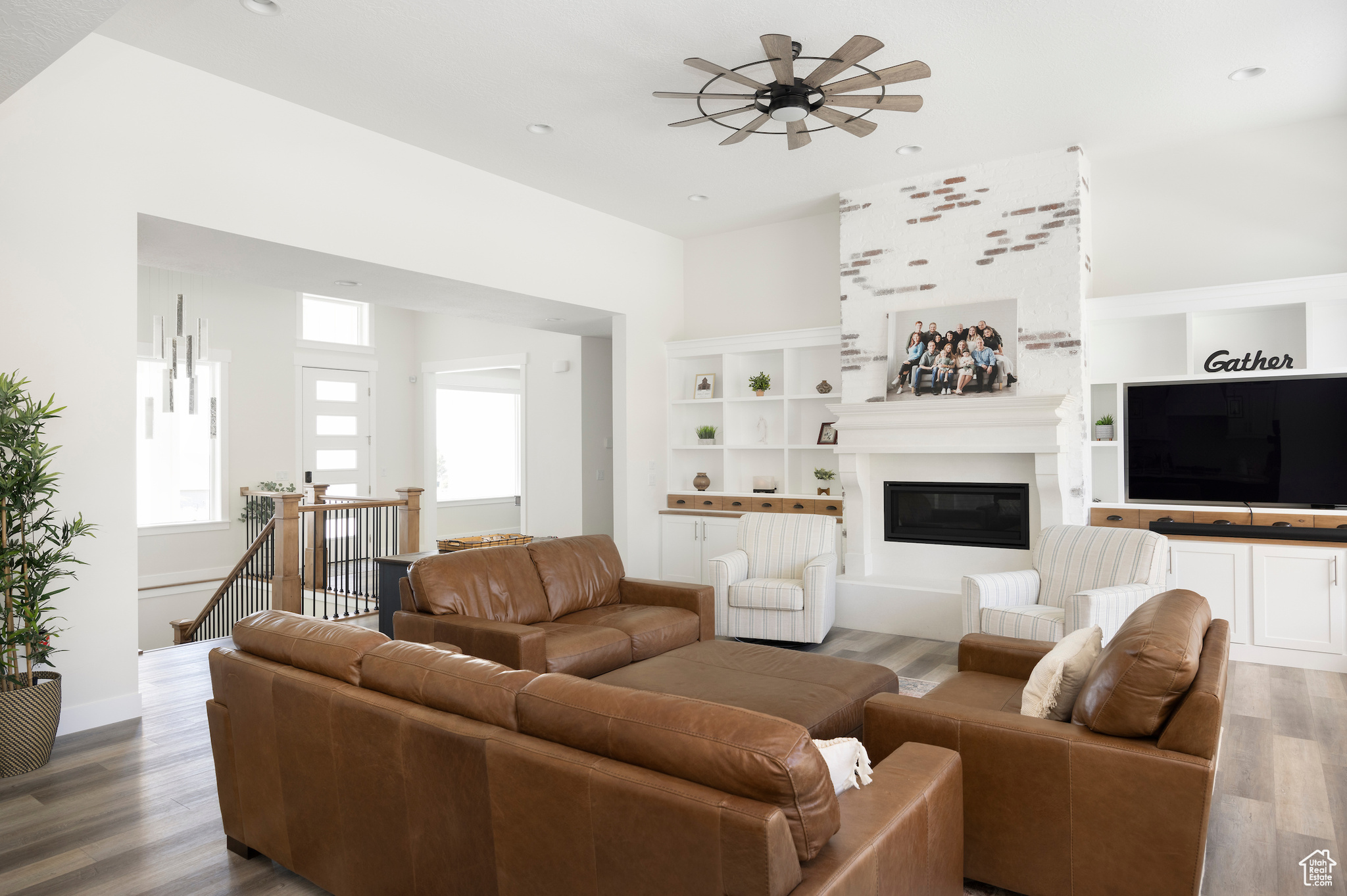 Living room with hardwood / wood-style flooring, built in shelves, and ceiling fan