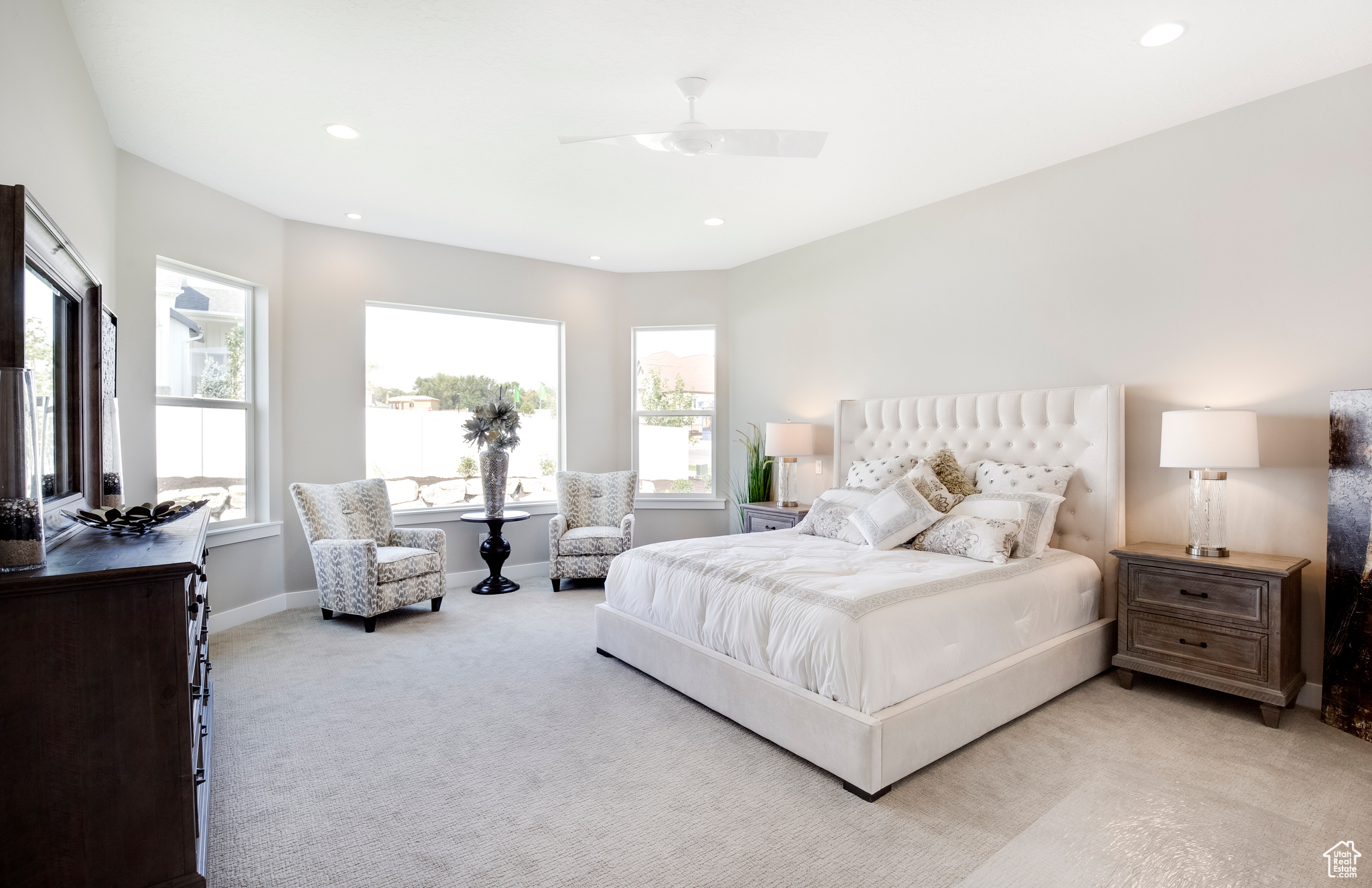 Bedroom featuring light colored carpet, ceiling fan, and multiple windows